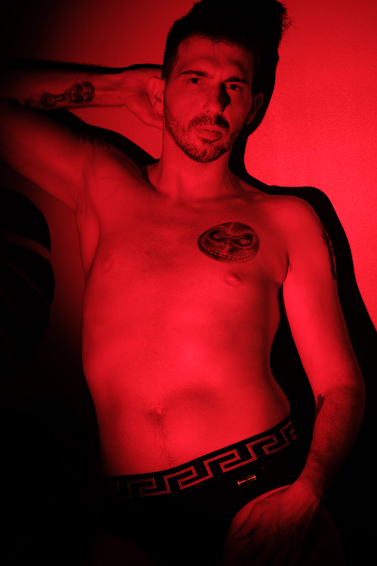 Portrait masculin de face éclairé en rouge, en sous-vêtements