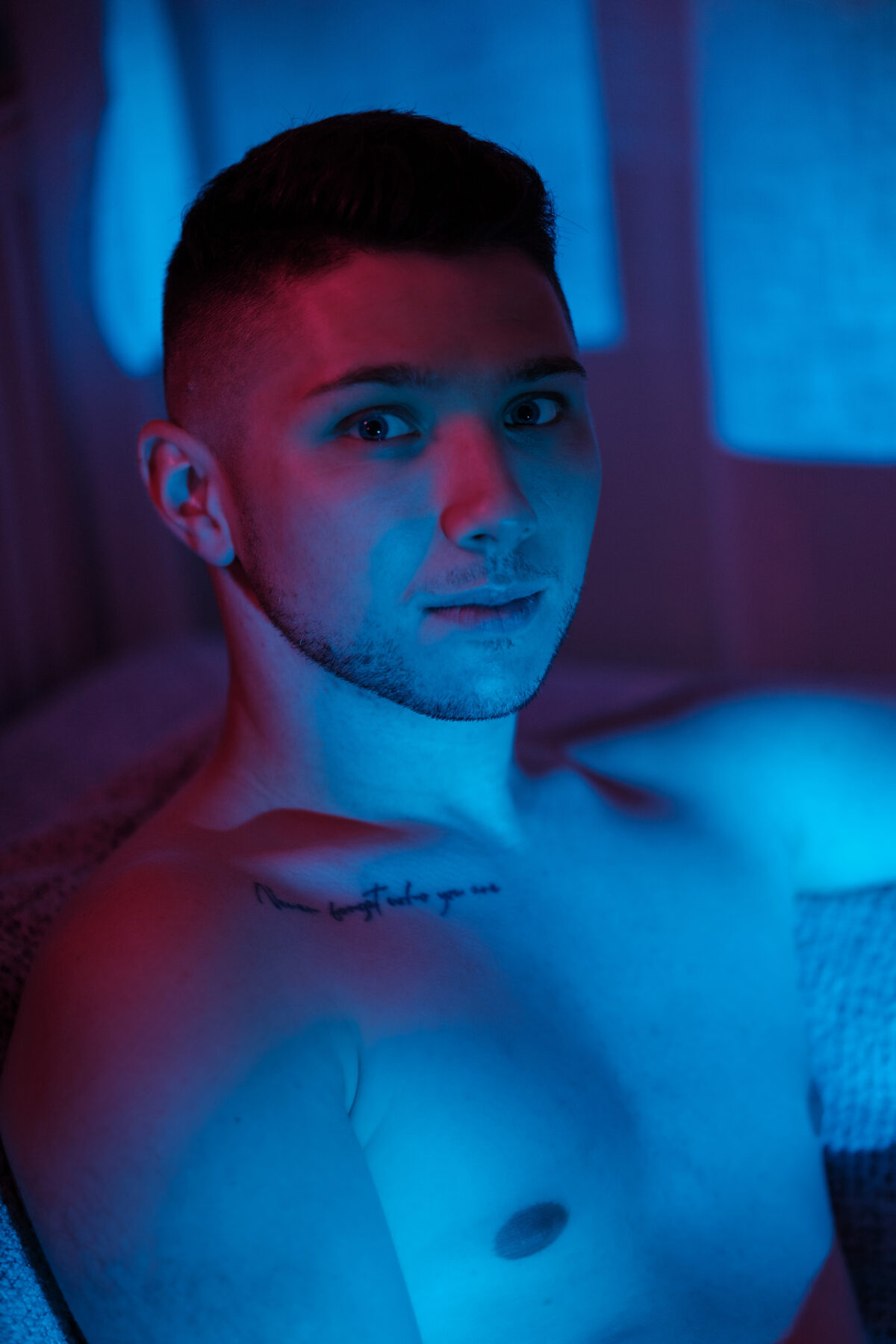 Portrait torse nu de William, regard de côté, éclairage bleu et rouge contrastés