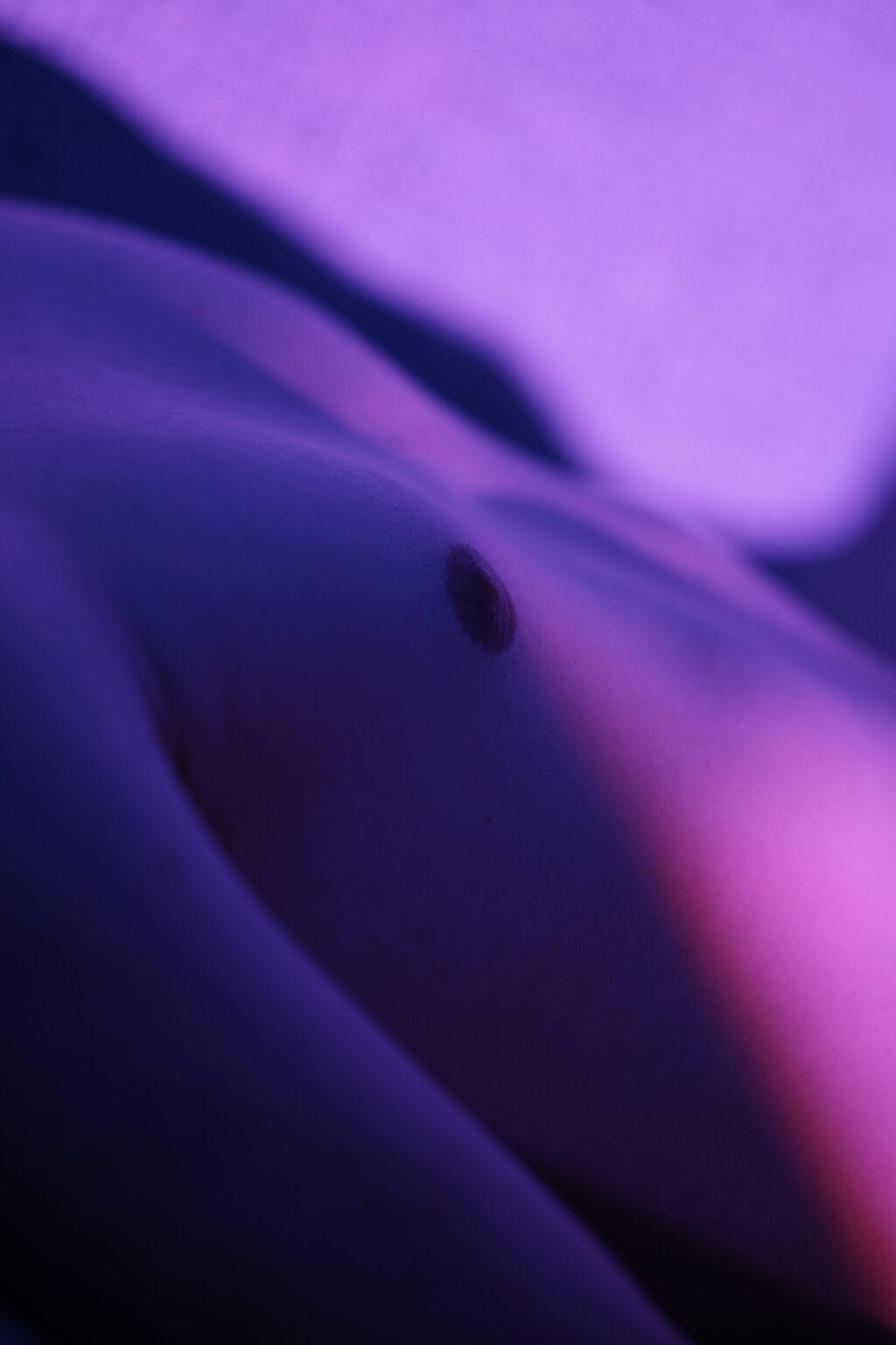 Photographie du corps d'un jeune homme, lumière violette