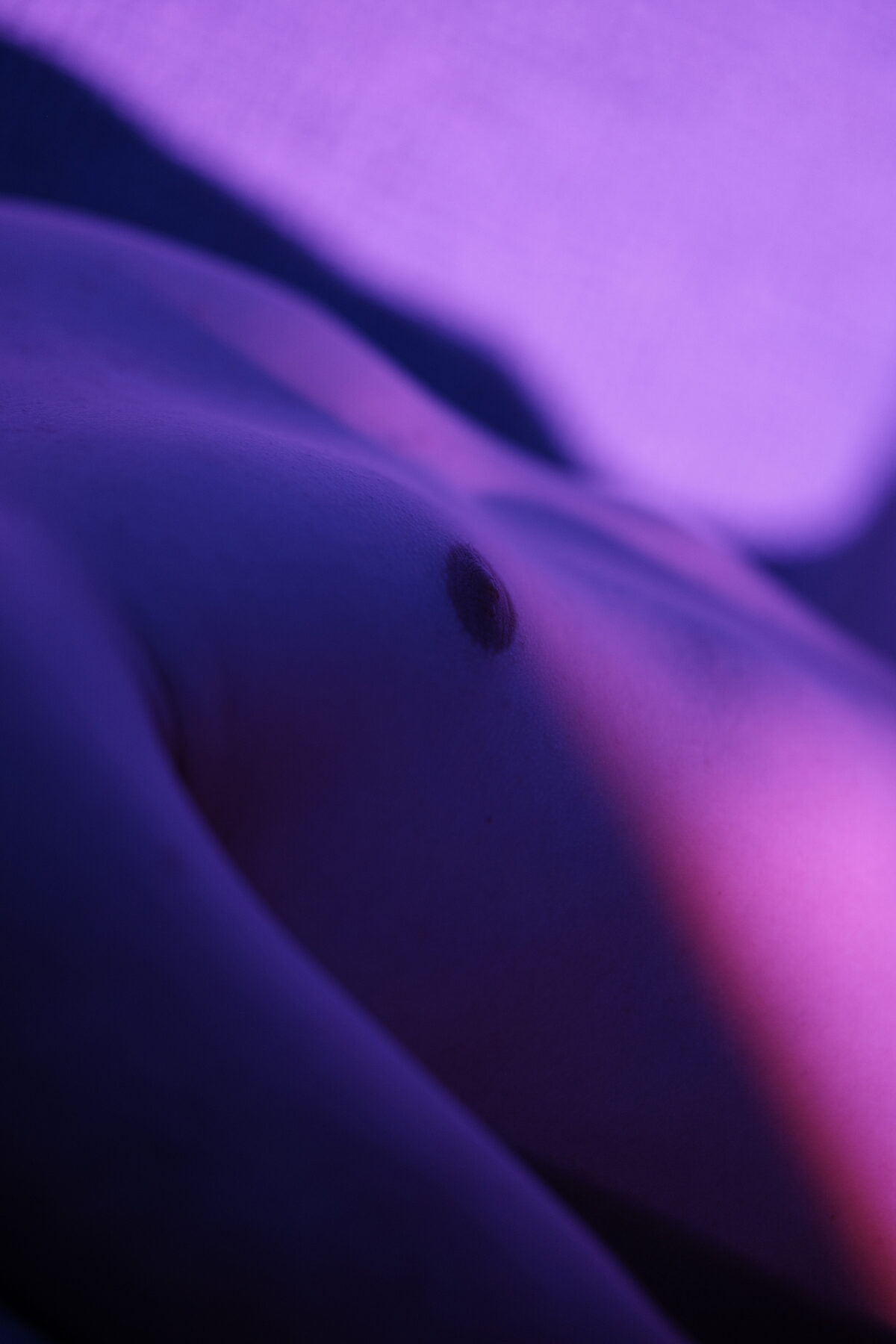Gros plan abstrait sur le torse de William, éclairage violet