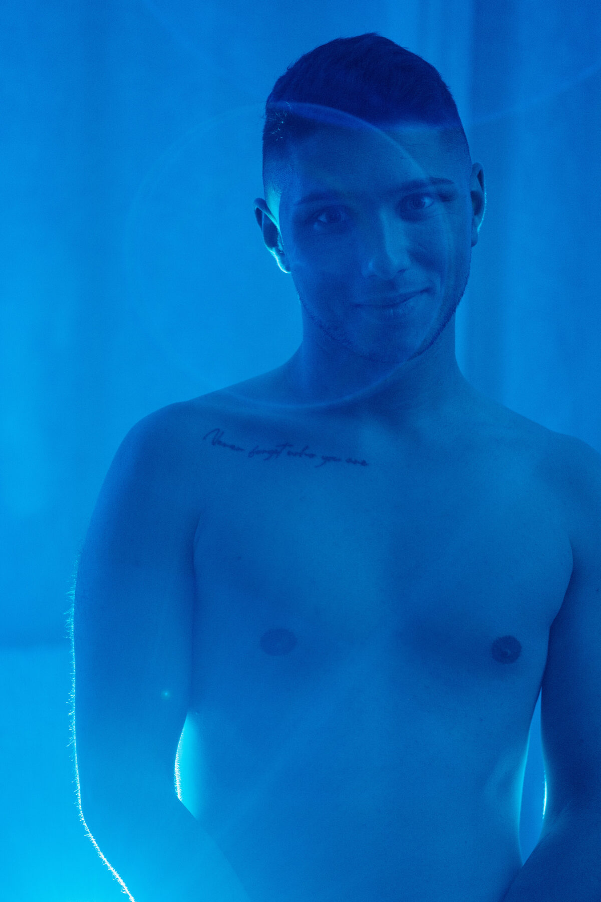 Portrait torse nu de William derrière un voile, éclairage bleu profond