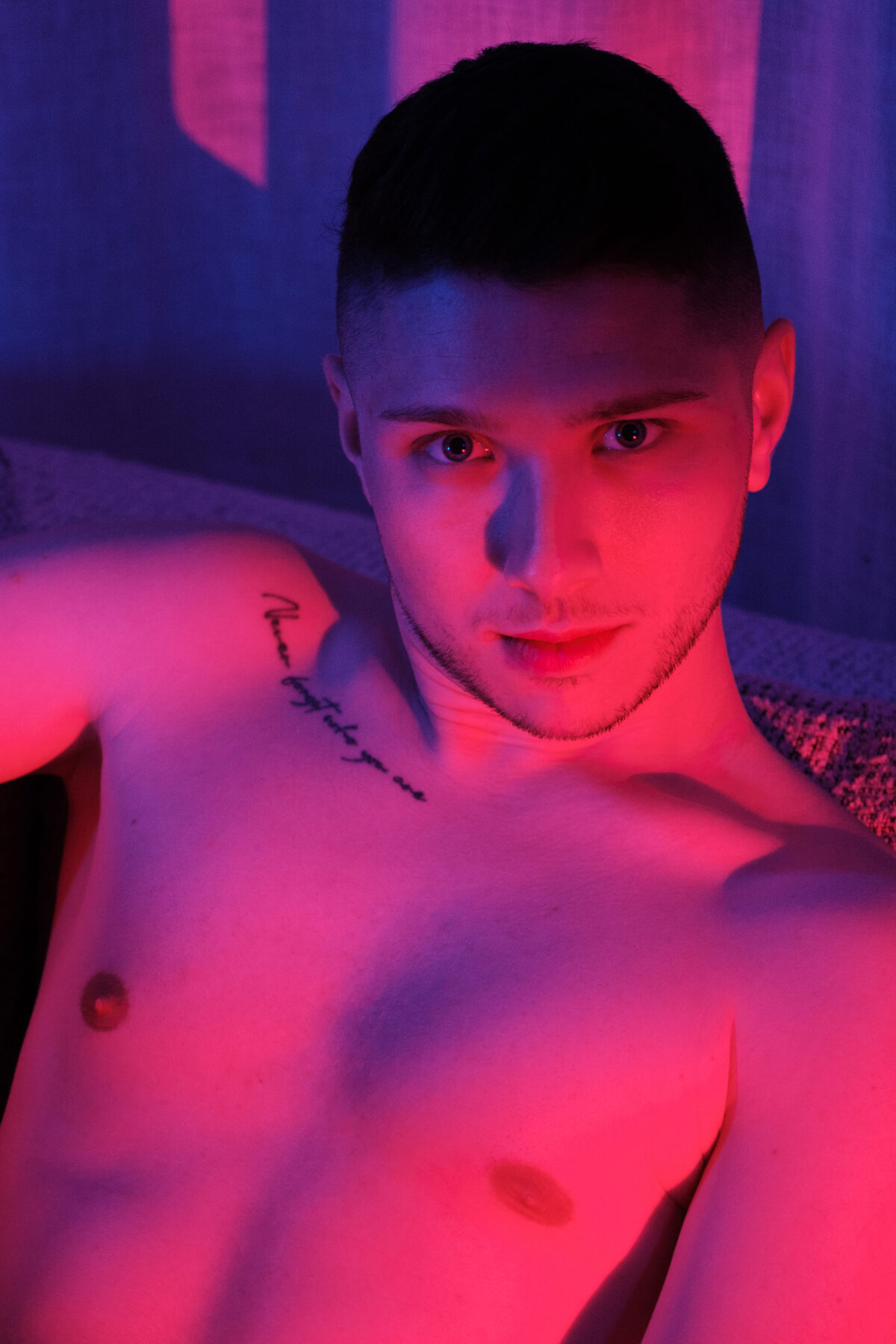 Portrait rapproché torse nu de William, éclairage rose et bleu