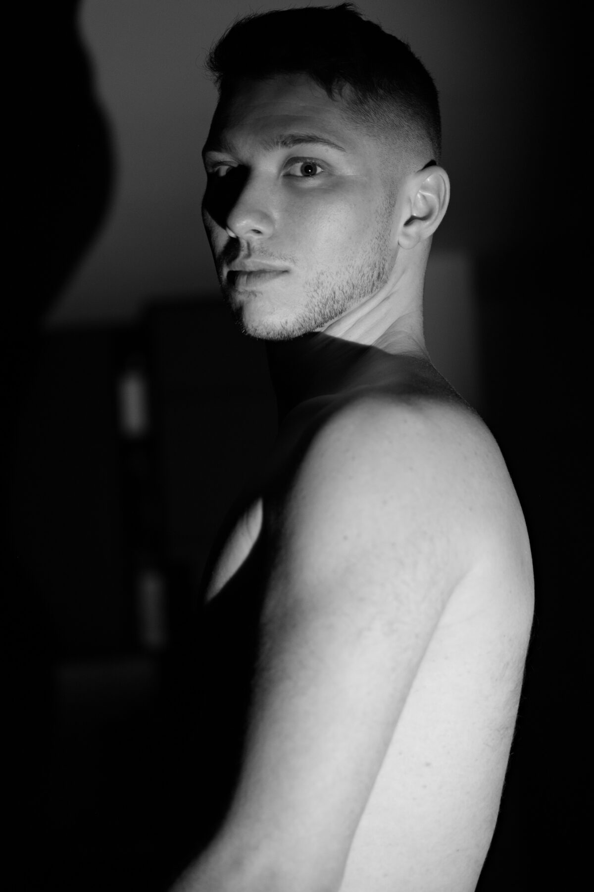 Portrait de profil de William, épaule et bras nus, noir et blanc, éclairage dramatique