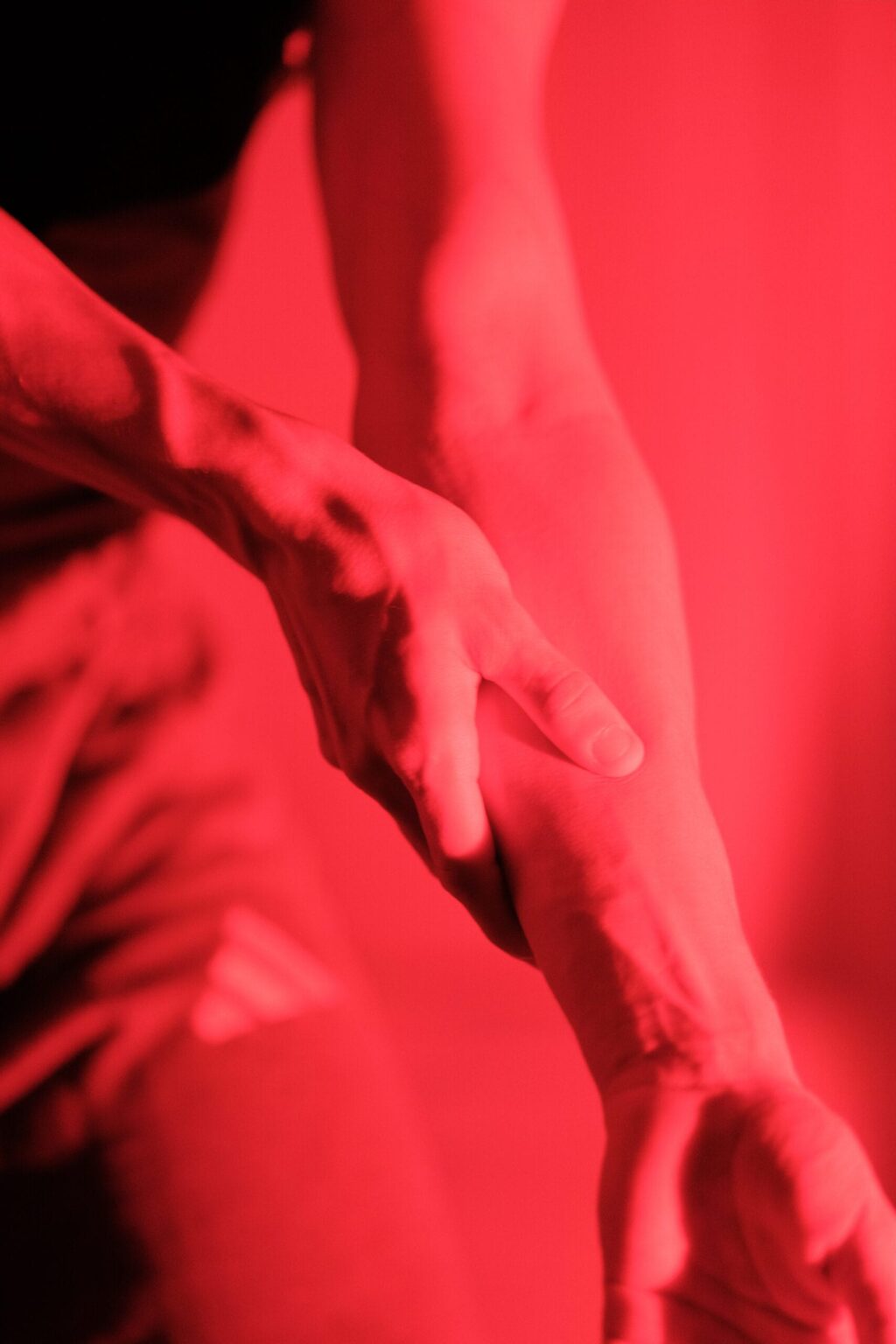 Emporgestreckter Arm von Gaston, in rotes Licht getaucht, tänzerische Geste – Bewegungsstudie