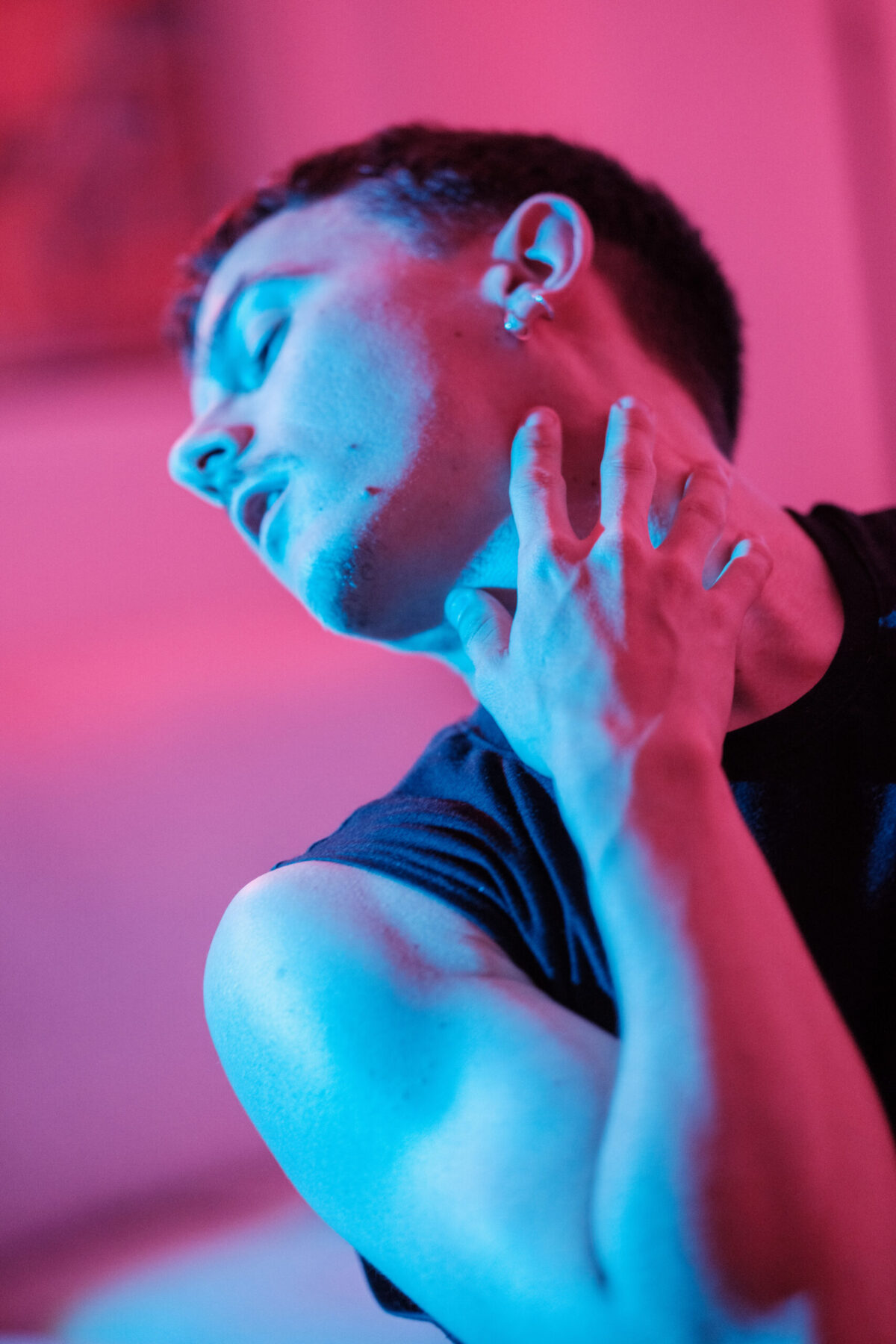 Gaston de profil, main levée près du visage, éclairage bleu et rose — pose de danseur
