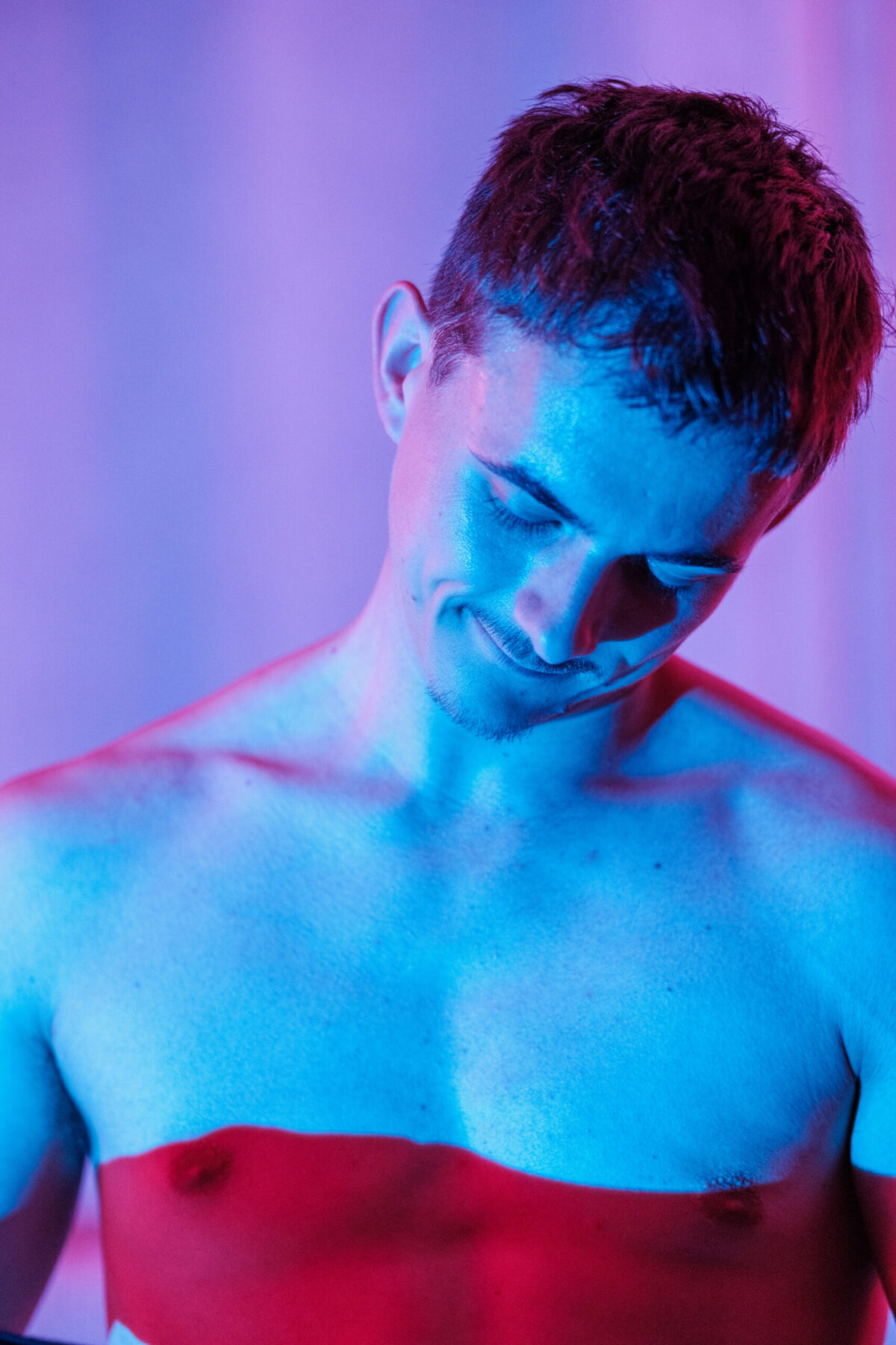 Gaston torse nu, éclairage bleu et rouge, sourire esquissé — portrait coloré
