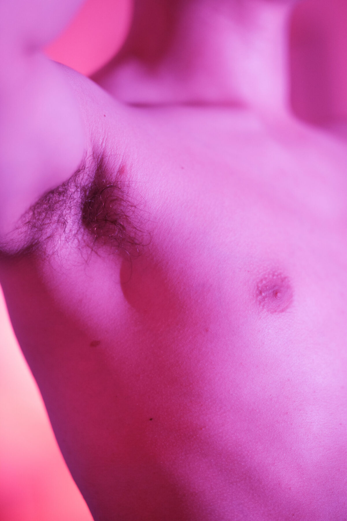 Détail du torse de Gaston en lumière magenta — étude corporelle abstraite