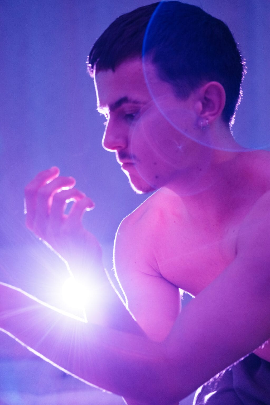 Gaston de profil, main éclairée par un flare, lumière bleue — pose de danseur