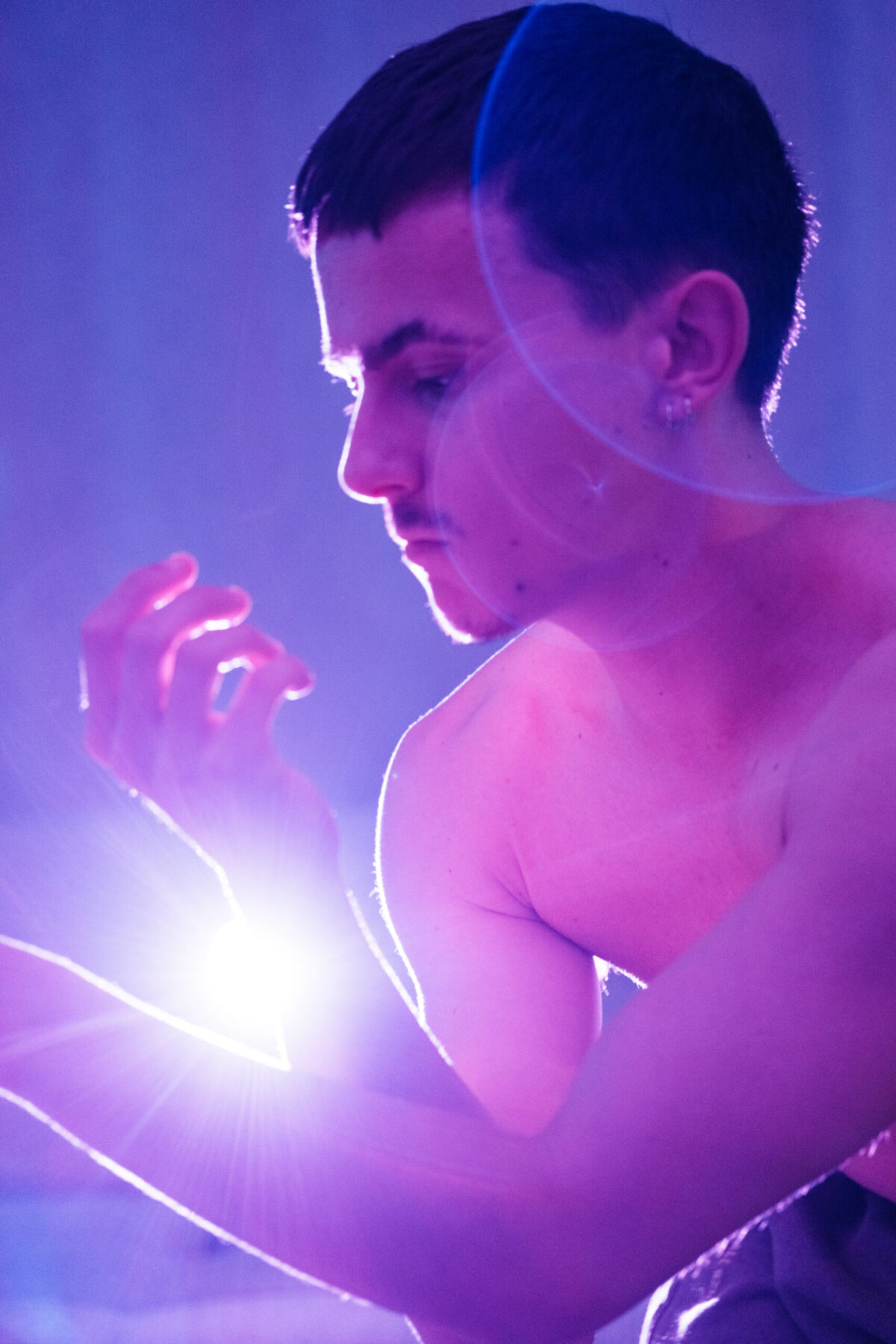Gaston de profil, main éclairée par un flare, lumière bleue — pose de danseur