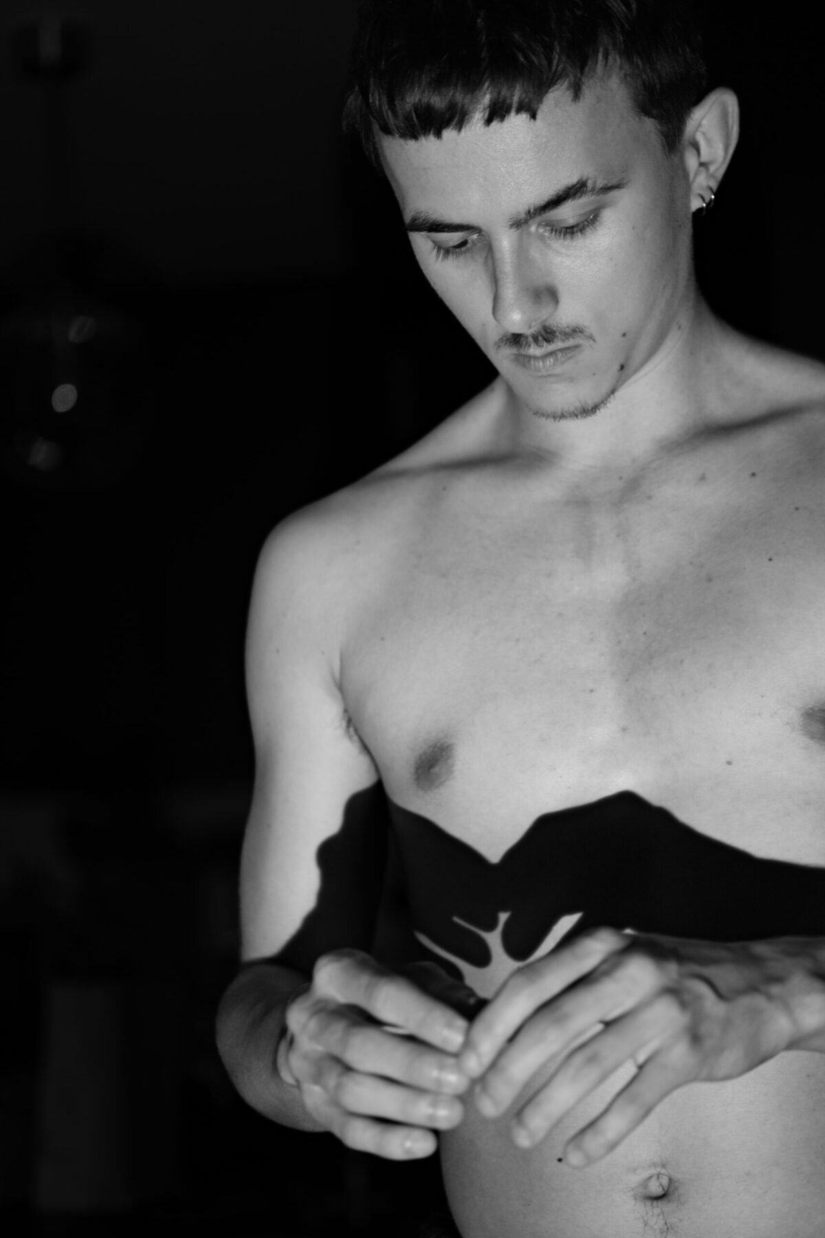 Gaston torse nu, tête baissée vers ses mains, pénombre — nu artistique intimiste
