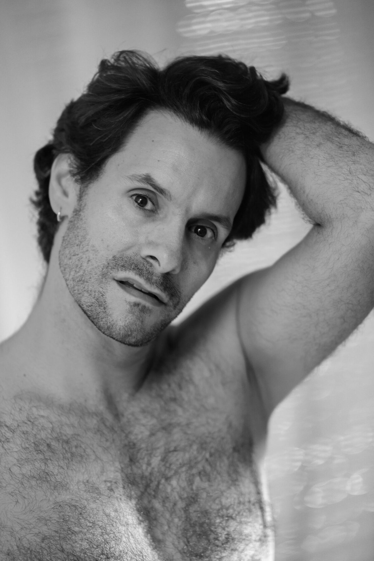 Portrait de Lucas en noir et blanc, mains dans les cheveux et expression intense