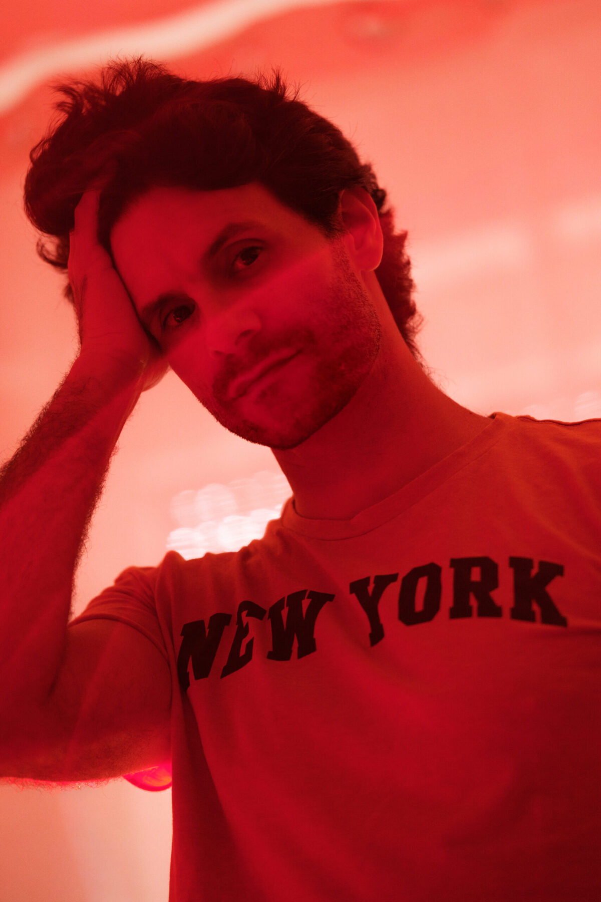 Portrait de Lucas sous lumière rouge, main dans les cheveux