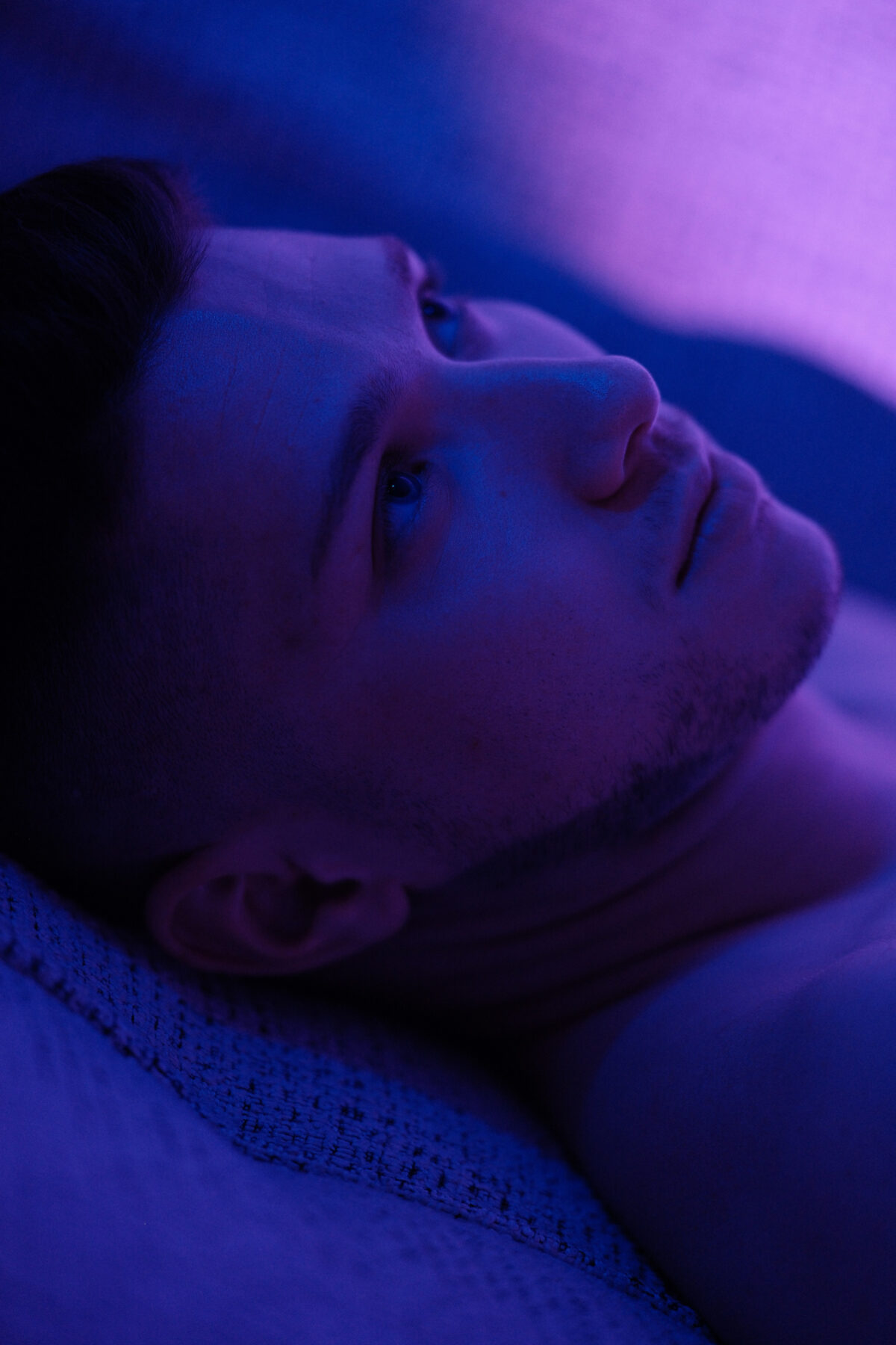 Portrait allongé de William, tête renversée, éclairage bleu et violet