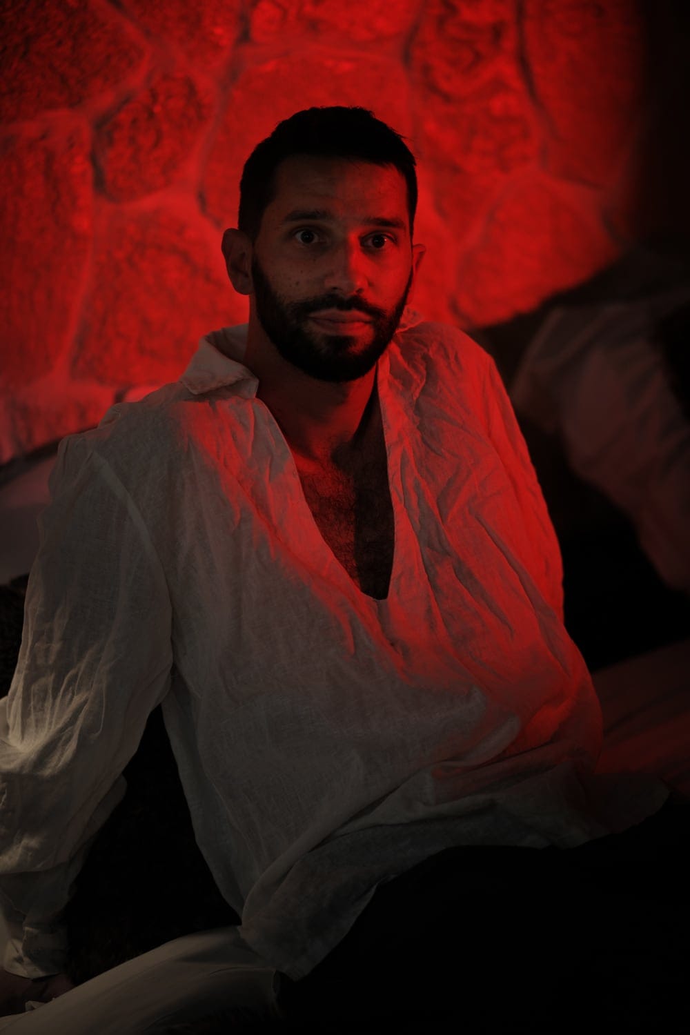 François assis, chemise claire ouverte, lumière rouge — portrait intimiste