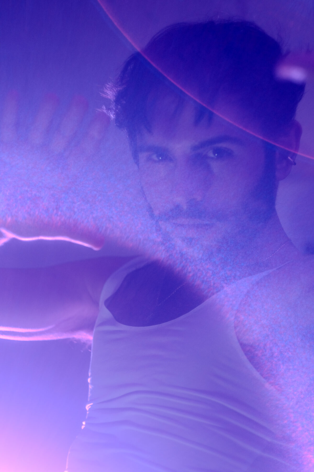 Portrait d'Hugo main levée sous une lumière violette diffuse et effet de flare