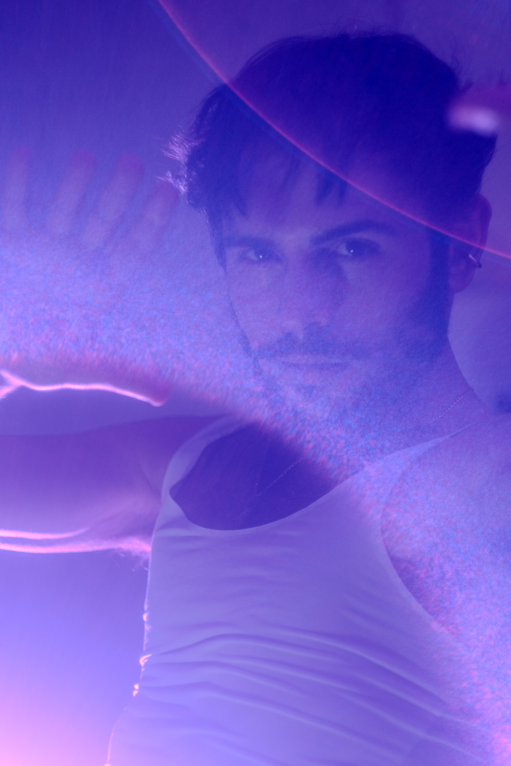 Portrait d'Hugo main levée sous une lumière violette diffuse et effet de flare