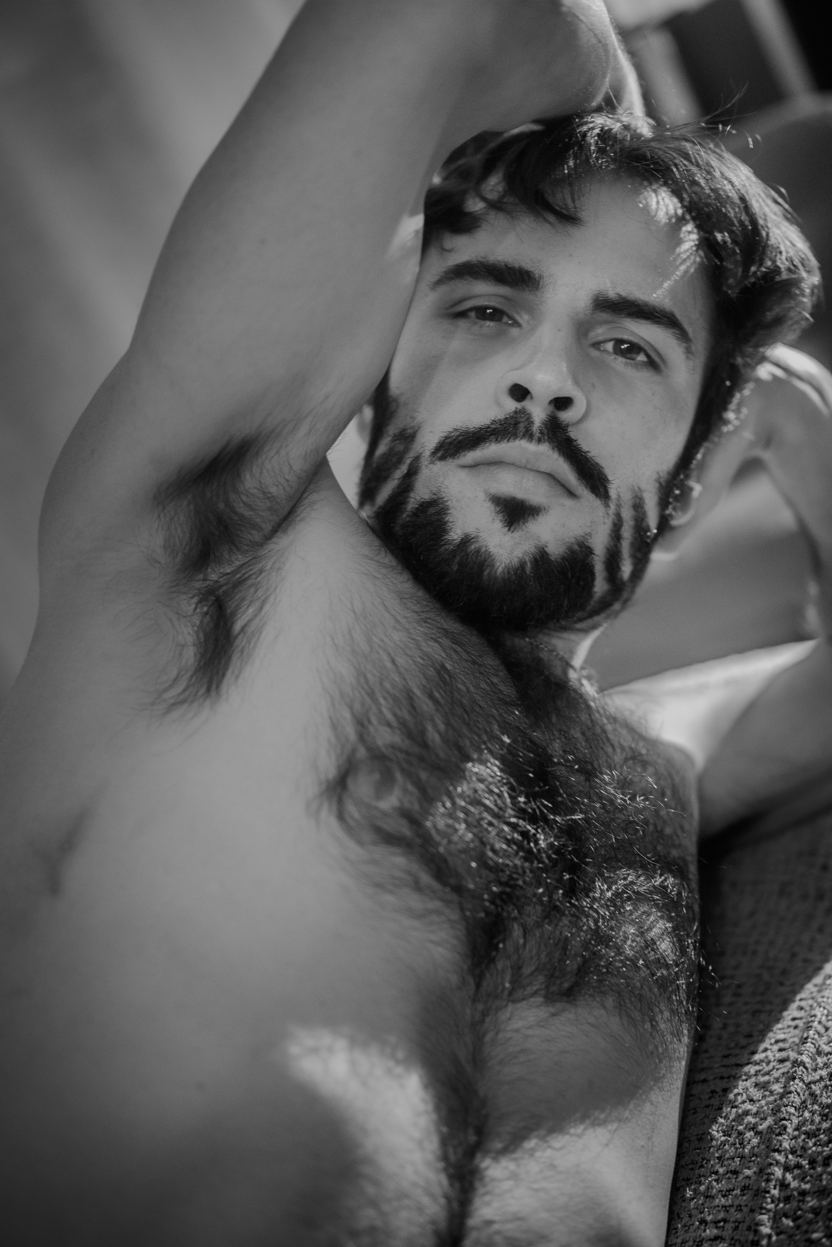 Portrait noir et blanc d'Hugo torse nu bras levé, regard direct vers l'objectif