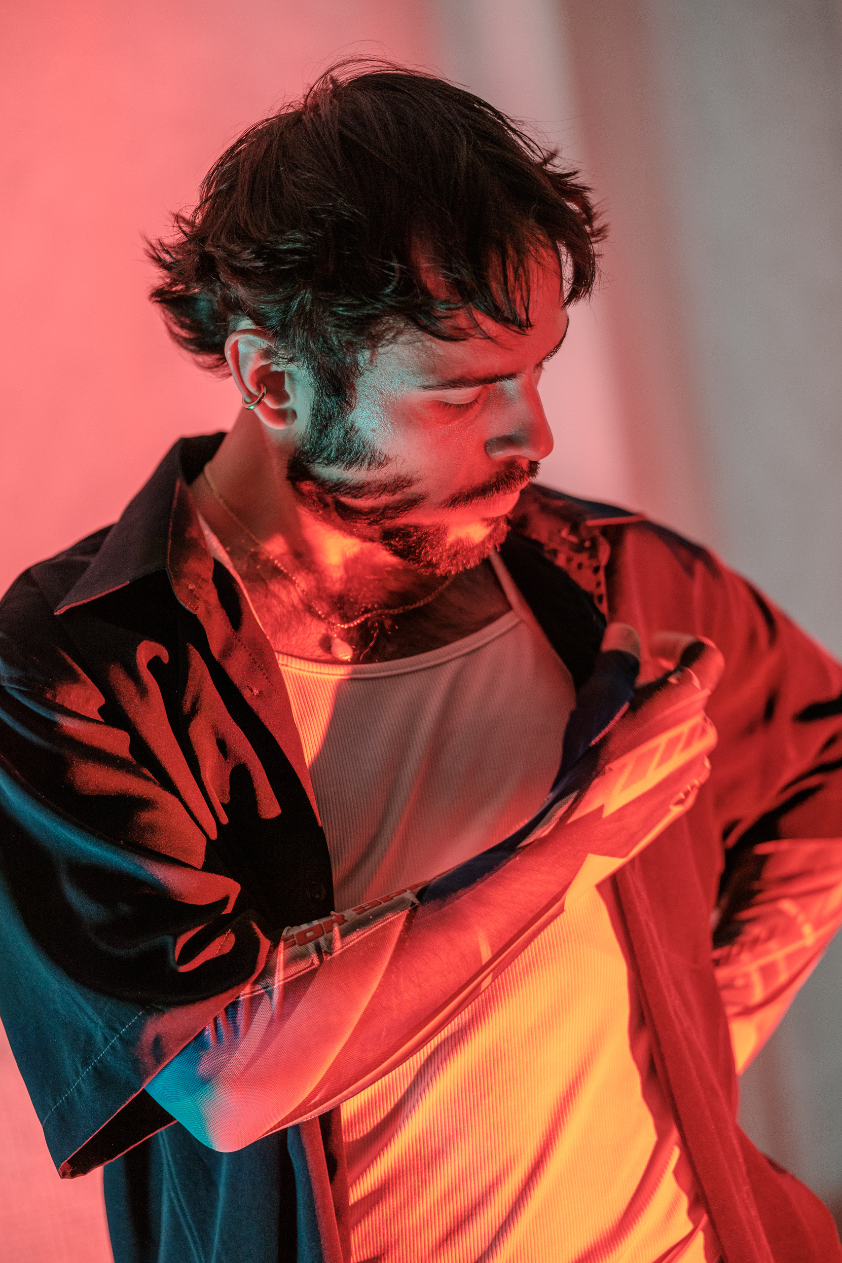Portrait de profil d'Hugo ajustant sa veste, éclairage contrasté rouge et bleu