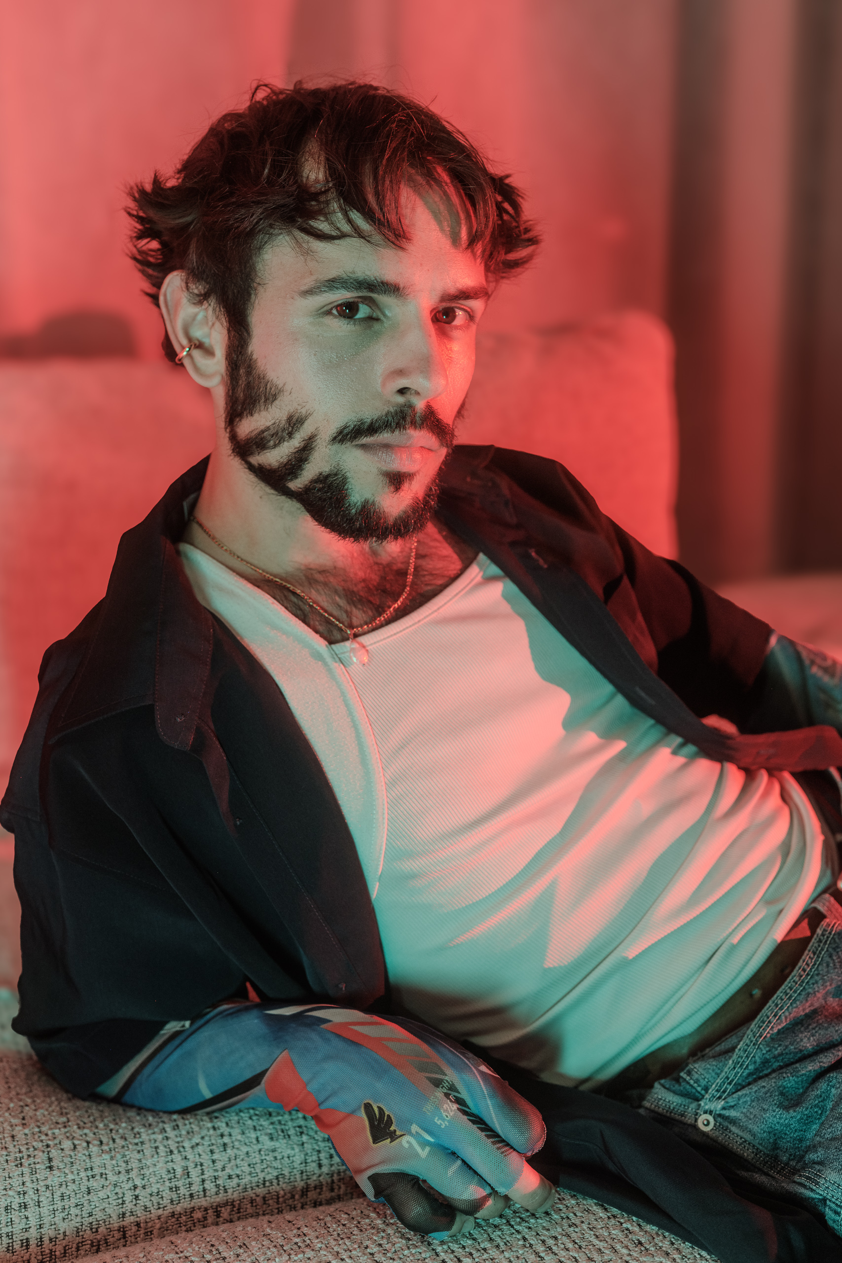 Portrait d'Hugo allongé en veste ouverte, ambiance lumineuse rouge et bleutée