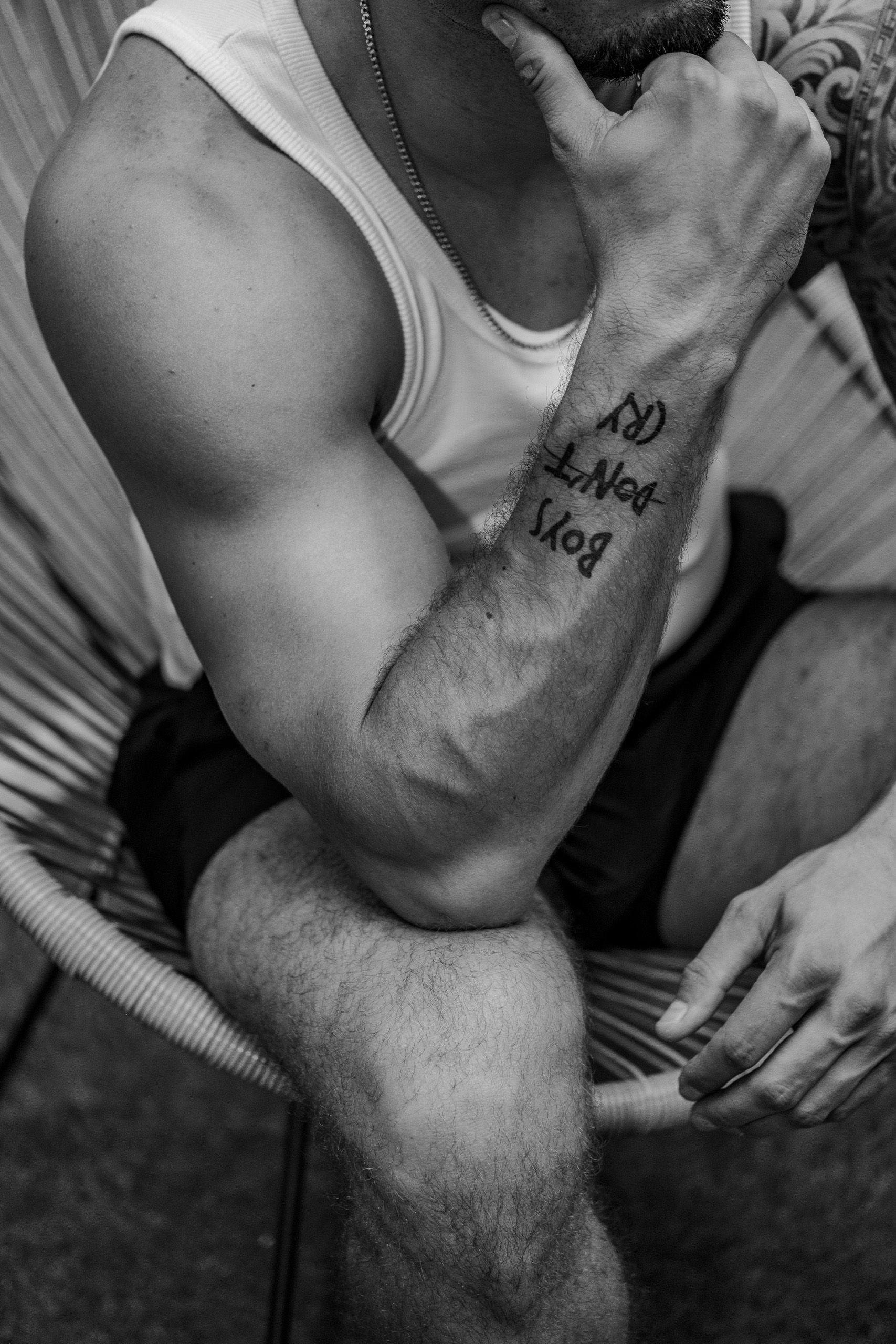 Vue de détail sur le bras et le tatouage "Boys don't cry" de KevinHungXL. Photo en noir et blanc
