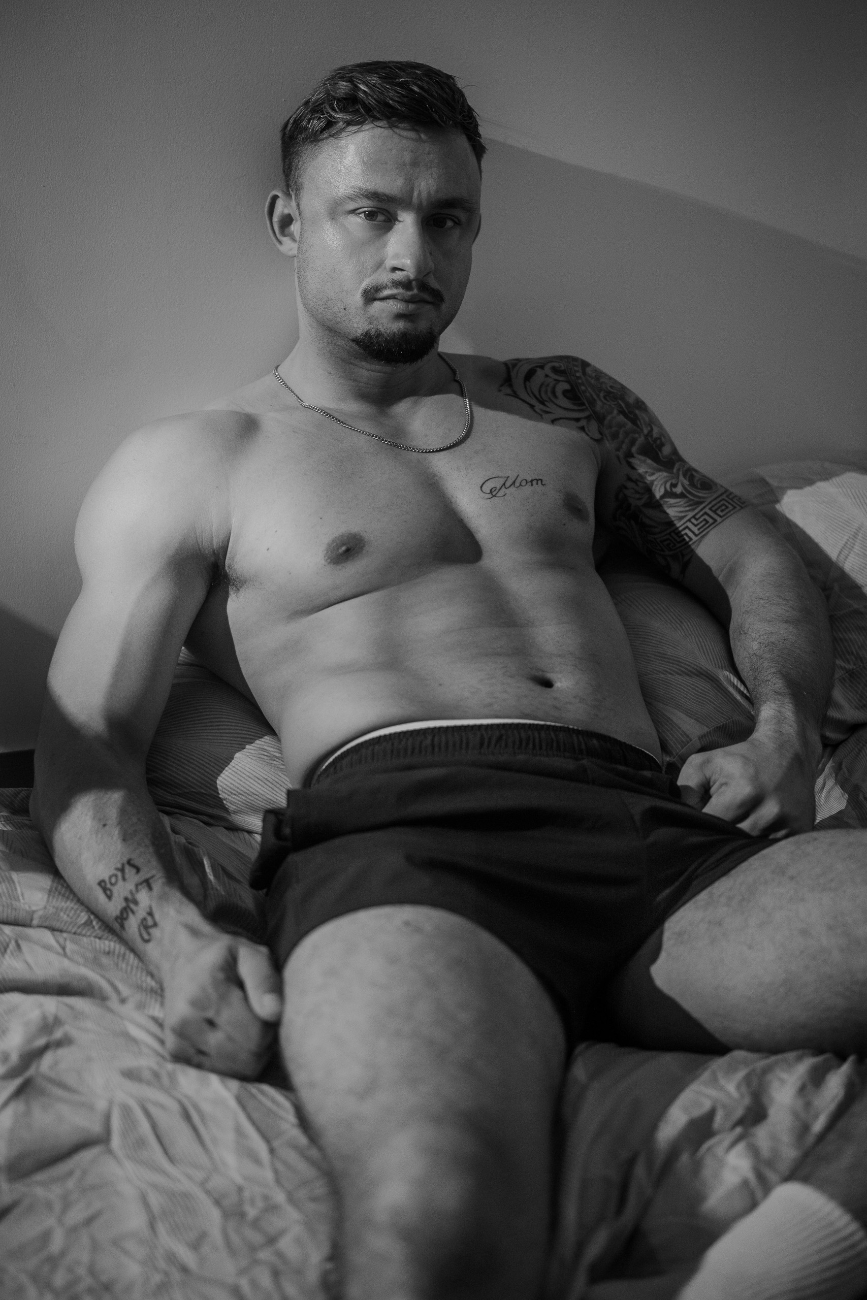 Portrait professionnel de KevinHungXL, en noir et blanc, regard face caméra, assis sur un lit