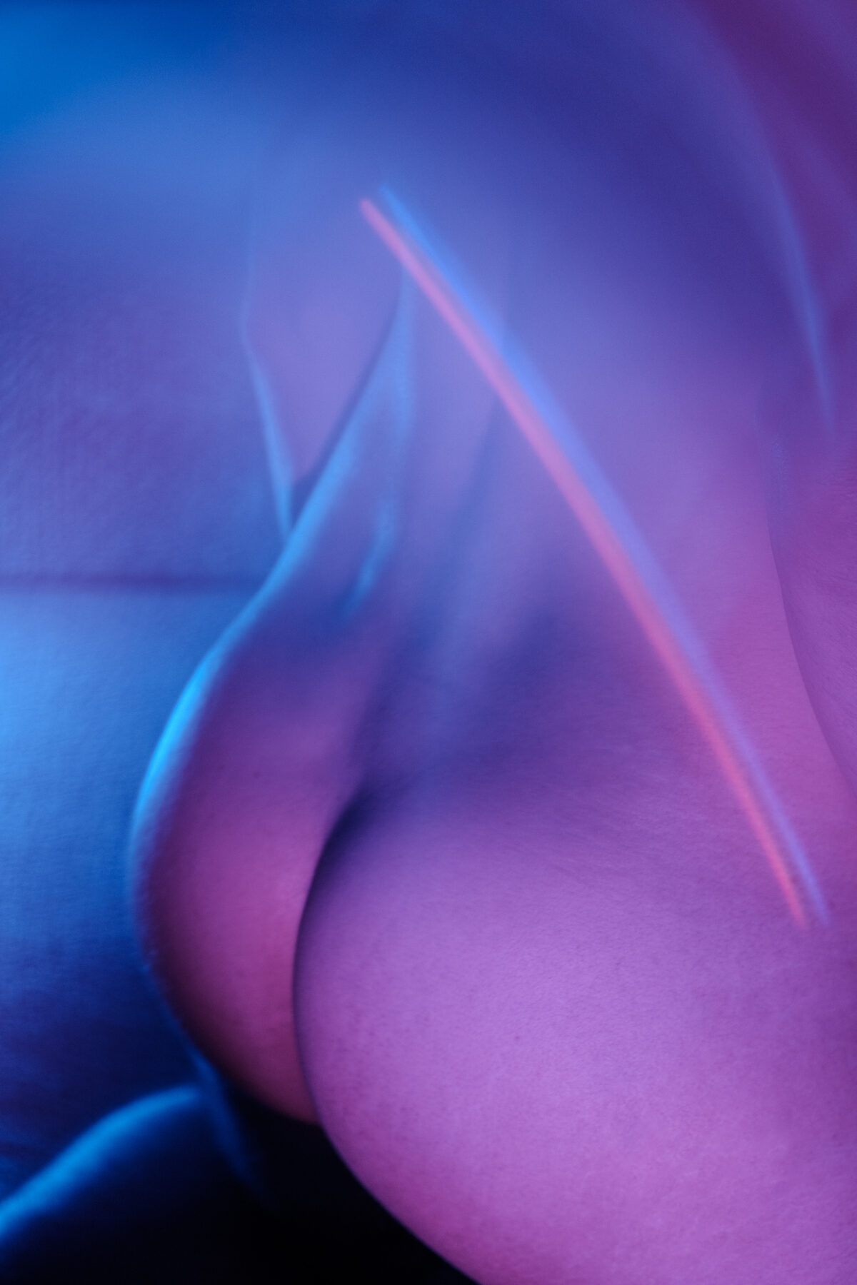 Gros plan abstrait sur le corps de Lionel, éclairage violet et bleu, jeu de courbes.