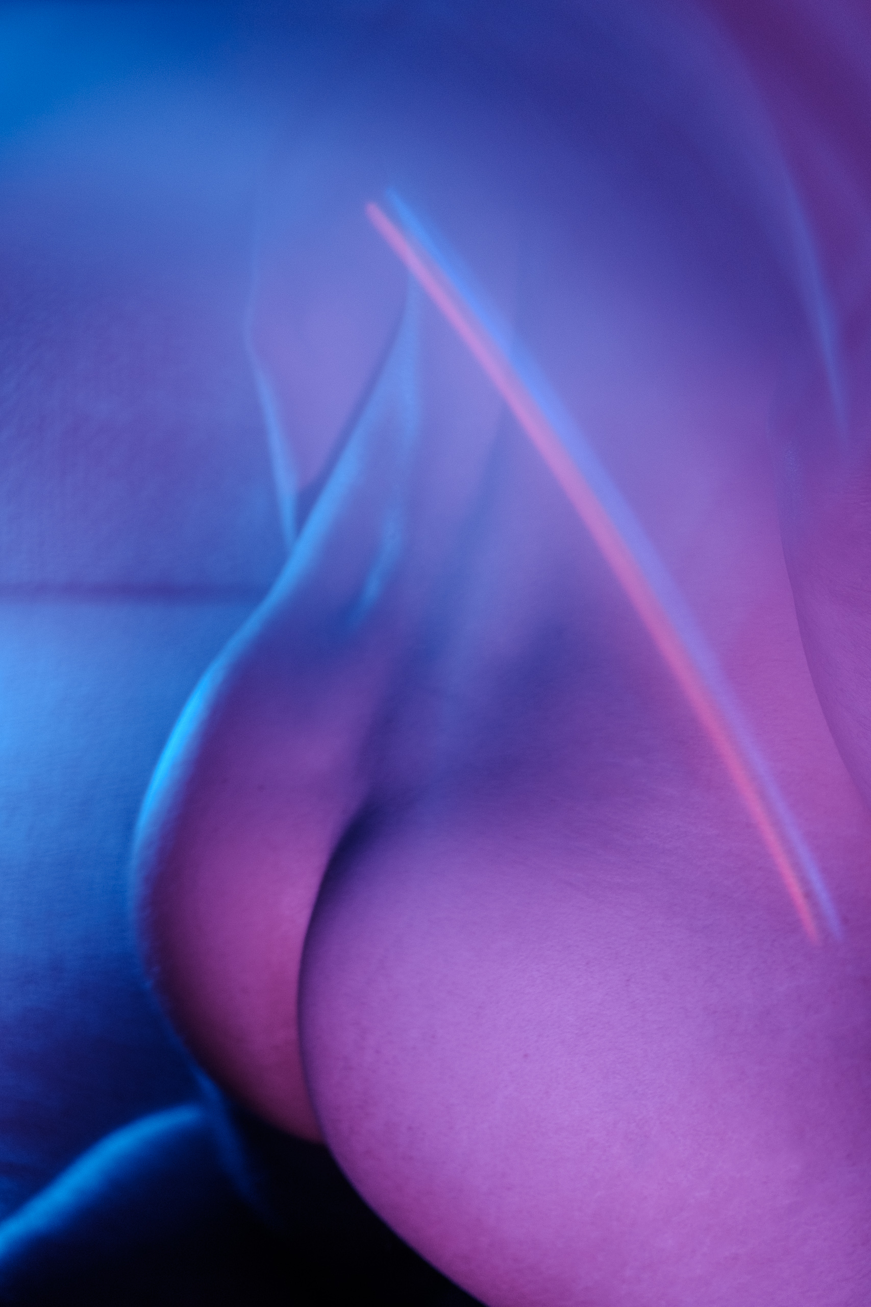 Gros plan abstrait sur le corps de Lionel, éclairage violet et bleu, jeu de courbes.