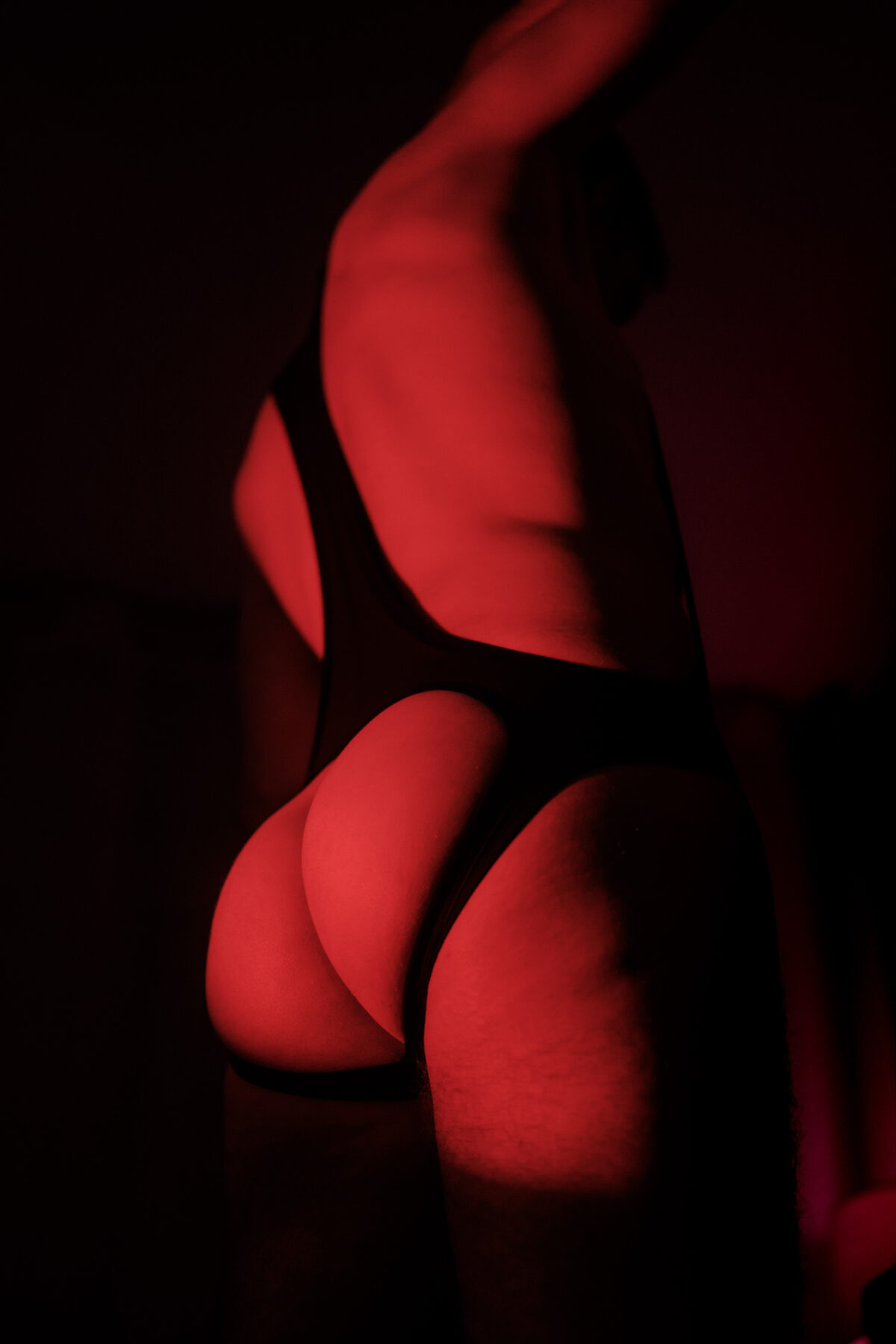 Silhouette de Lionel de dos en contre-jour rouge, nu artistique, jeu d'ombres marqué.