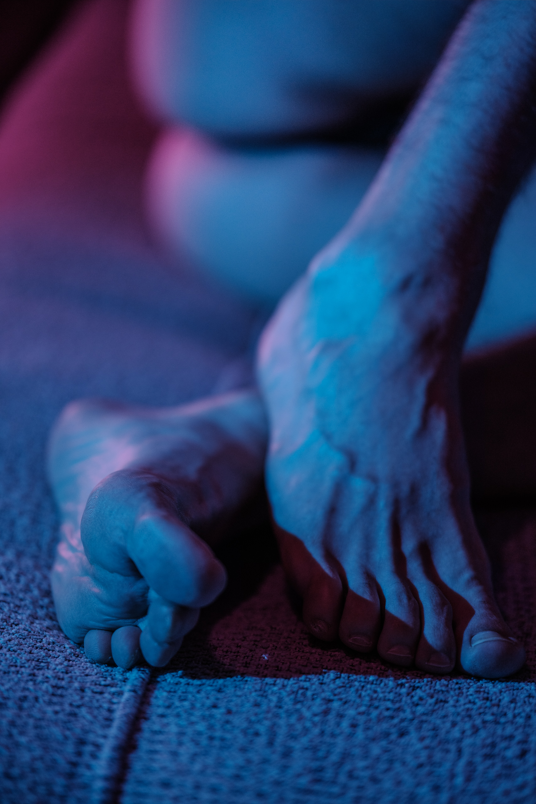 Gros plan sur les pieds de Lionel, éclairage bleu nuit, ambiance feutrée.