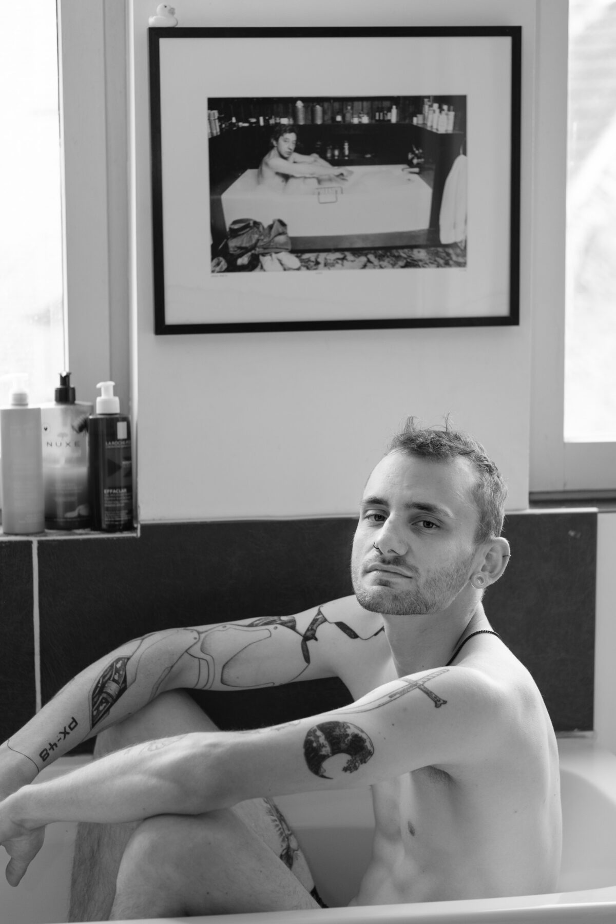 Vincent sitzt in einer Badewanne unter einem Gainsbourg-Rahmen, schwarz-weiß