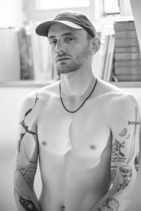Portrait noir et blanc de Vincent, torse nu, tatouages visibles, lumière naturelle