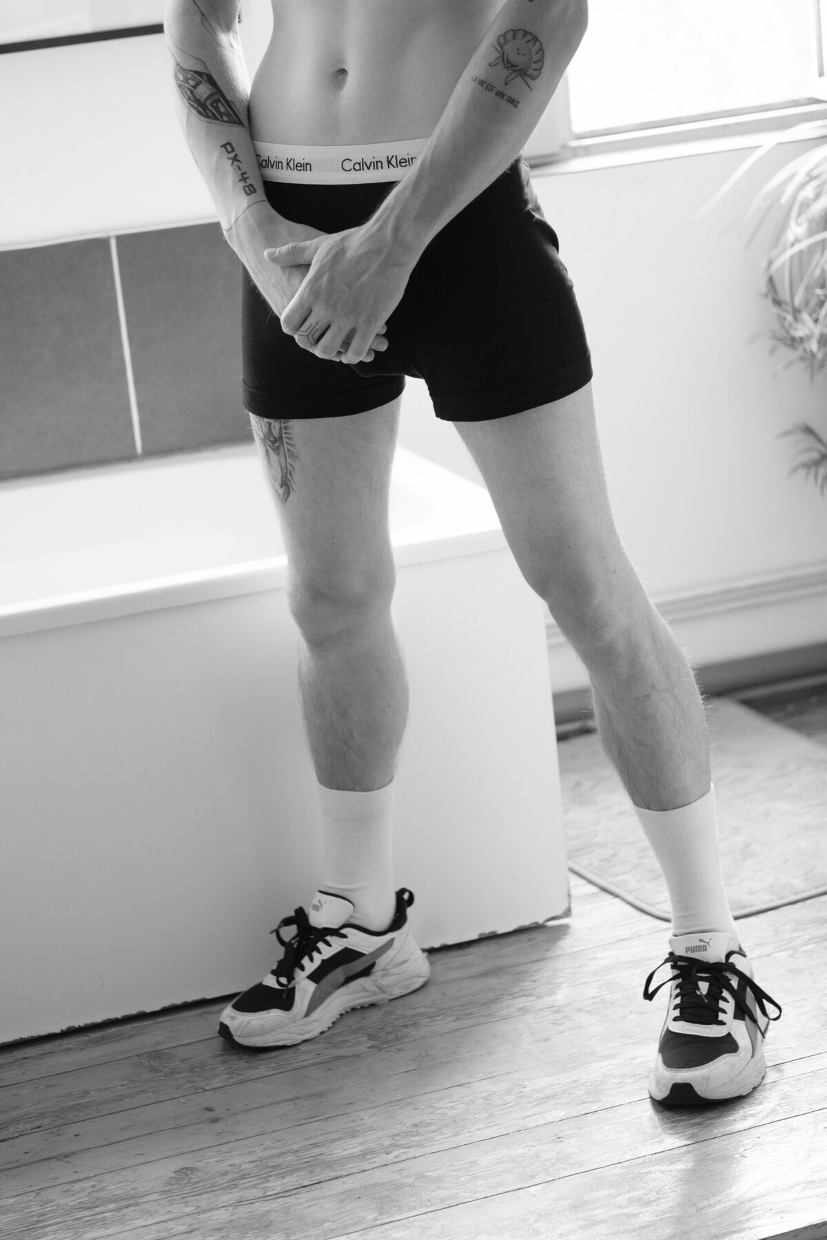 Vincent in Unterwäsche und Sneakers in einem Badezimmer, Schwarz und Weiß