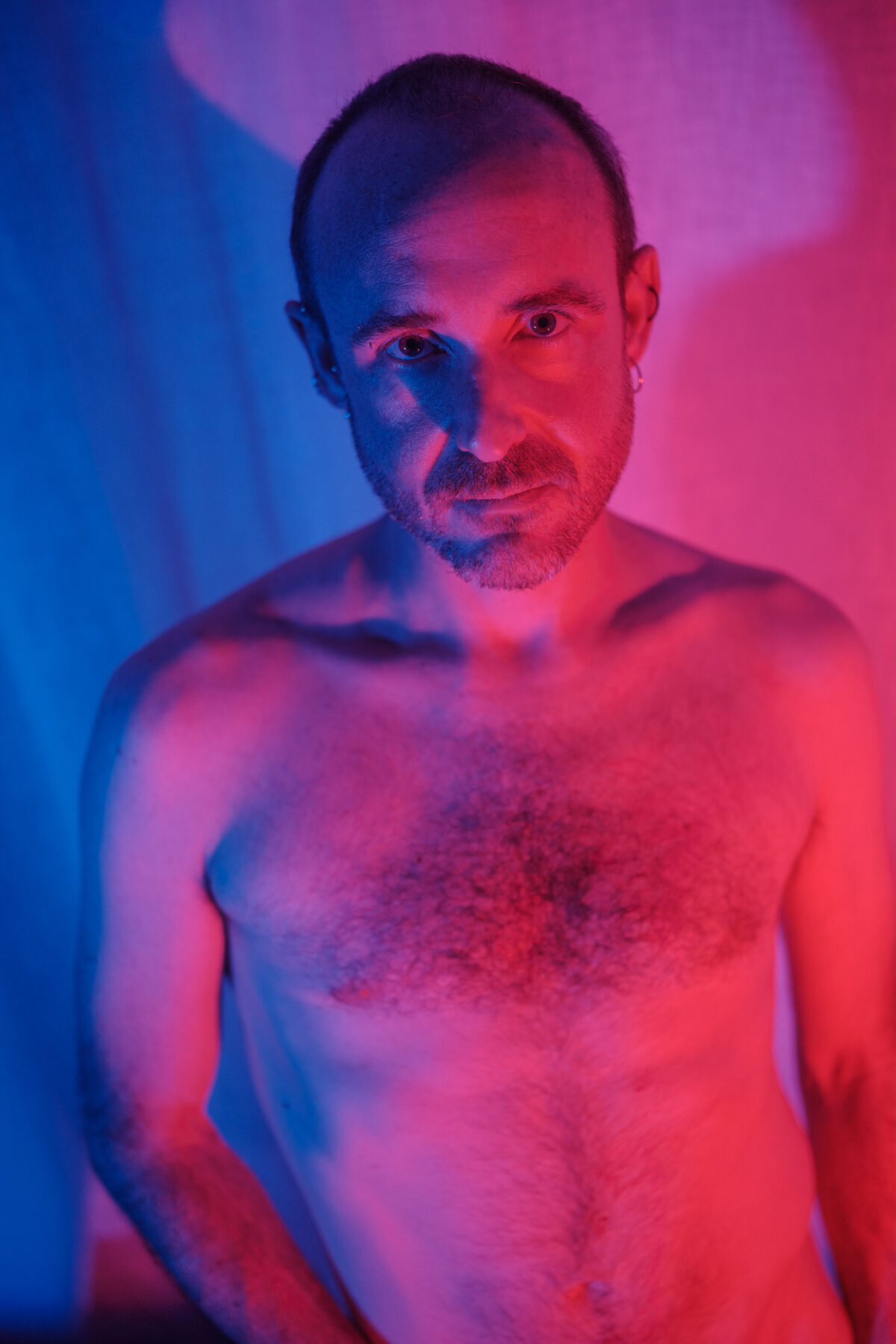 Porträt von Clément, mit freiem Oberkörper, rot-blaue Zweifarbbeleuchtung.