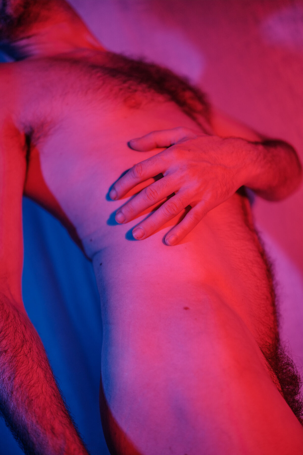 Großaufnahme von Cléments Oberkörper, Hand auf der Schulter, rote Beleuchtung.