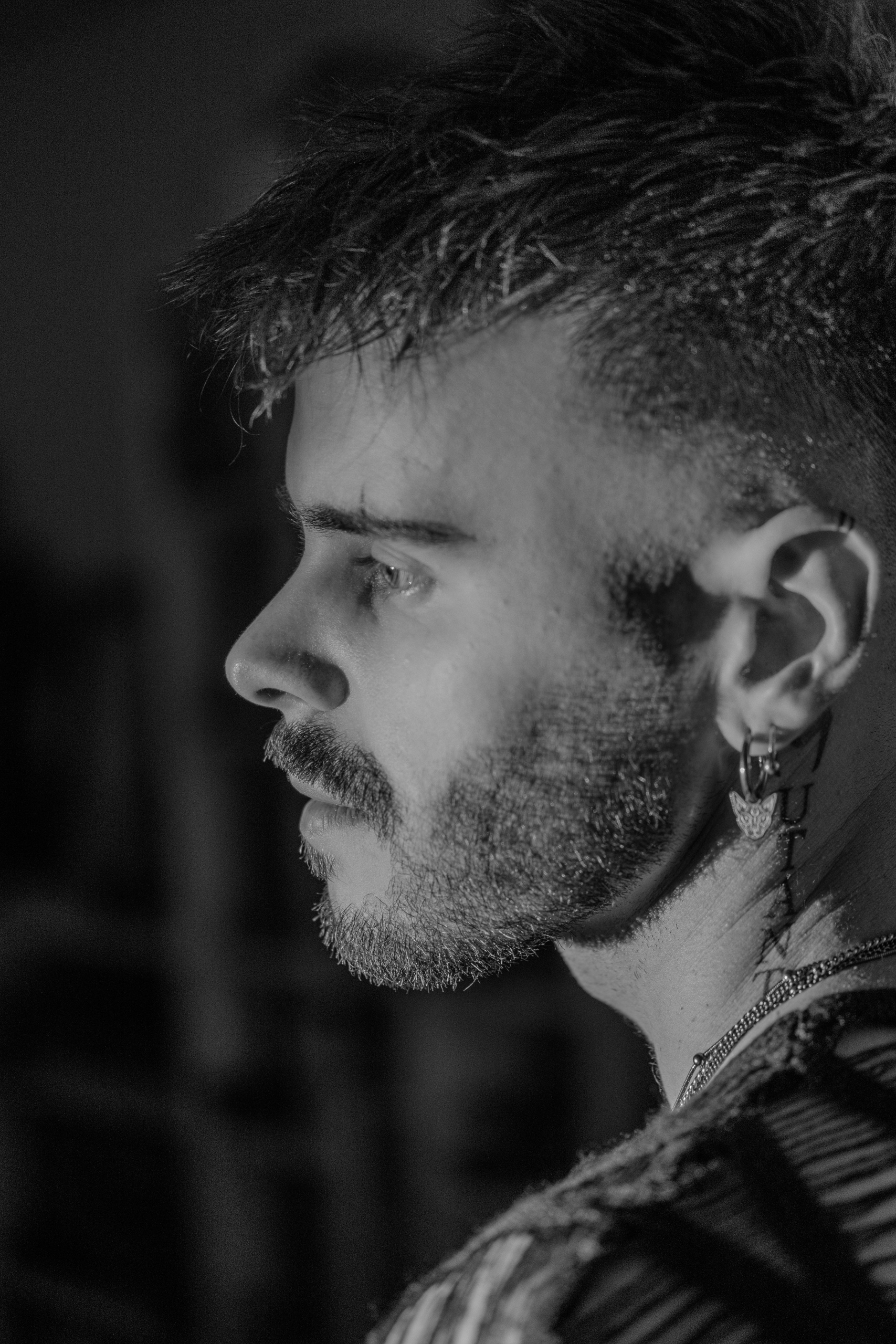 Portrait de profil en noir et blanc, boucle d'oreille, ambiance contrastée.