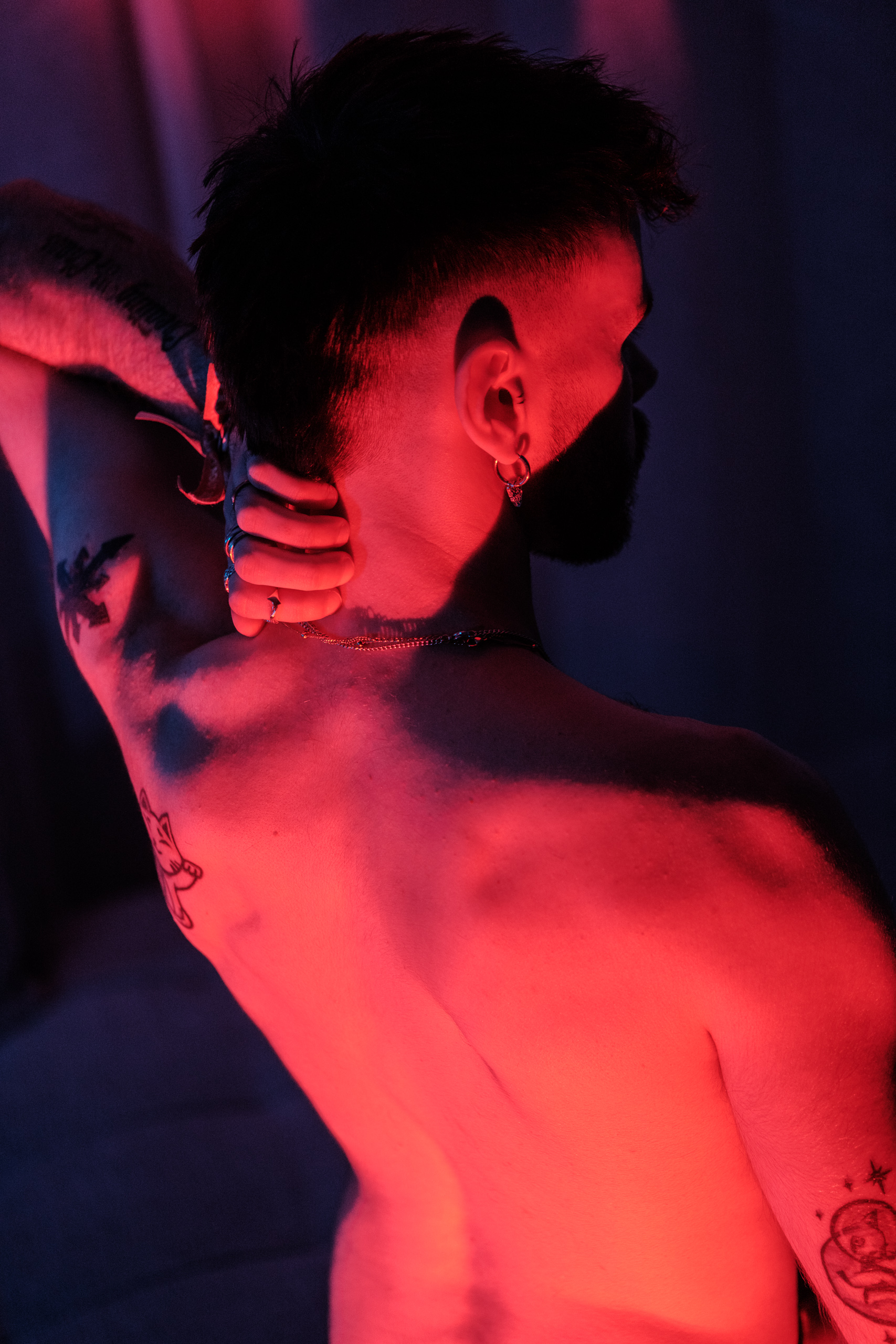 Portrait de dos, tatouages et bijoux, éclairage rouge.