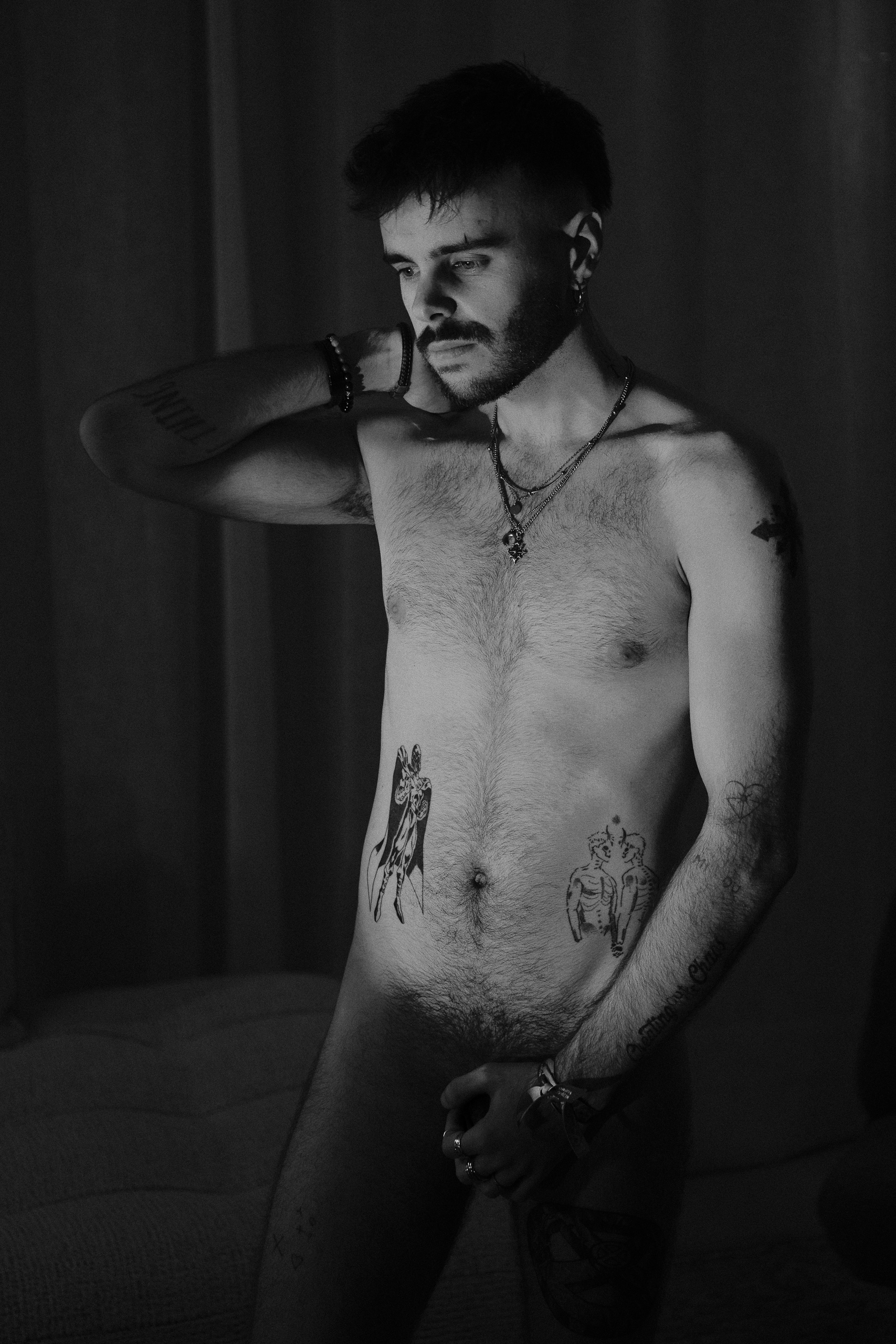 Nu artistique debout en noir et blanc, tatouages, ambiance feutrée.