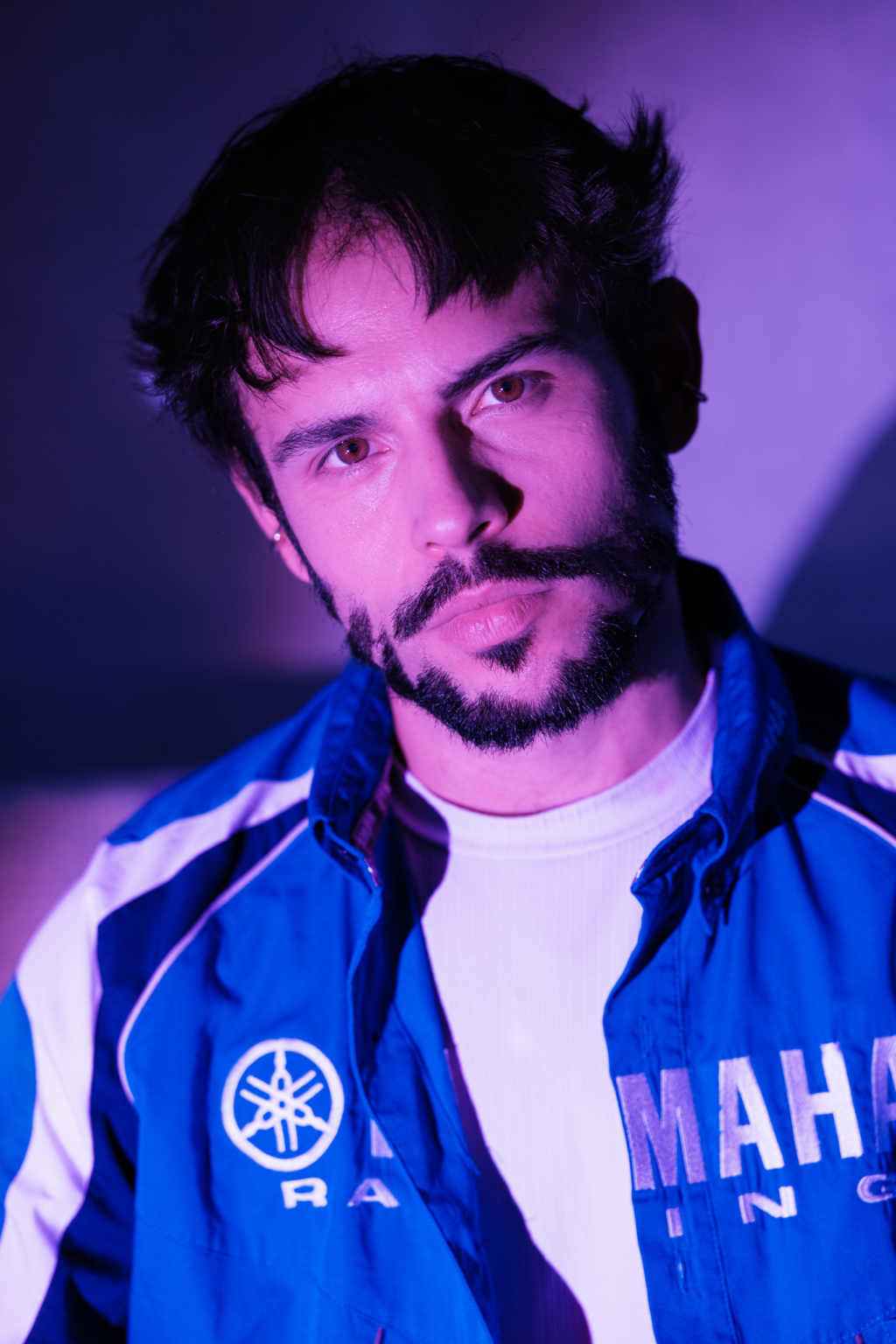 Hugo, portrait masculin en lumière bleu-violet, blouson Yamaha Racing, regard direct