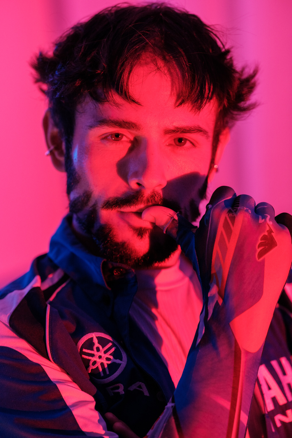 Hugo, portrait homme barbu en lumière rouge, main près du visage, blouson Yamaha