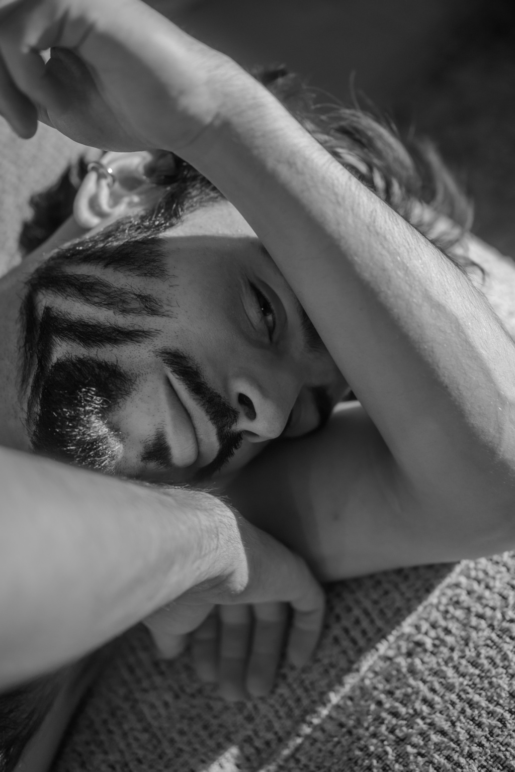Gros plan du visage d'Hugo, bras replié devant le visage, portrait noir et blanc rapproché