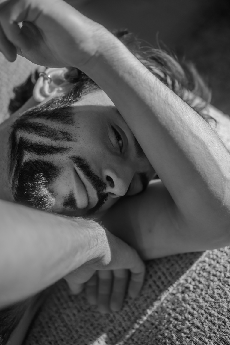 Gros plan du visage d'Hugo, bras replié devant le visage, portrait noir et blanc rapproché