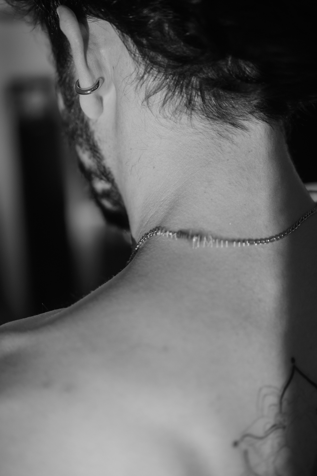 Détail de la nuque d'Hugo, chaîne fine et piercing d'oreille, portrait noir et blanc