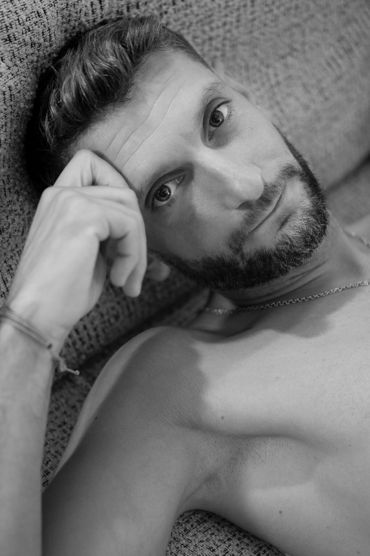 Portrait rapproché noir et blanc de Loukas More, allongé, regard vers le haut, expression naturelle.
