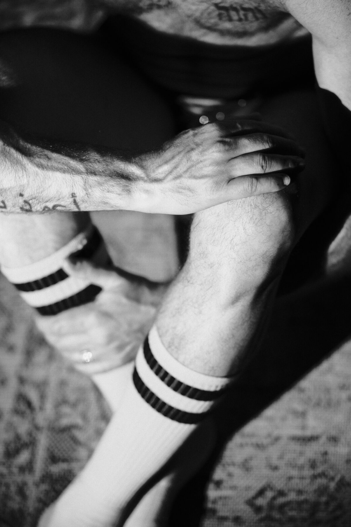 Gros plan noir et blanc sur des mains jointes et des bracelets rayés, détail textile et corporel