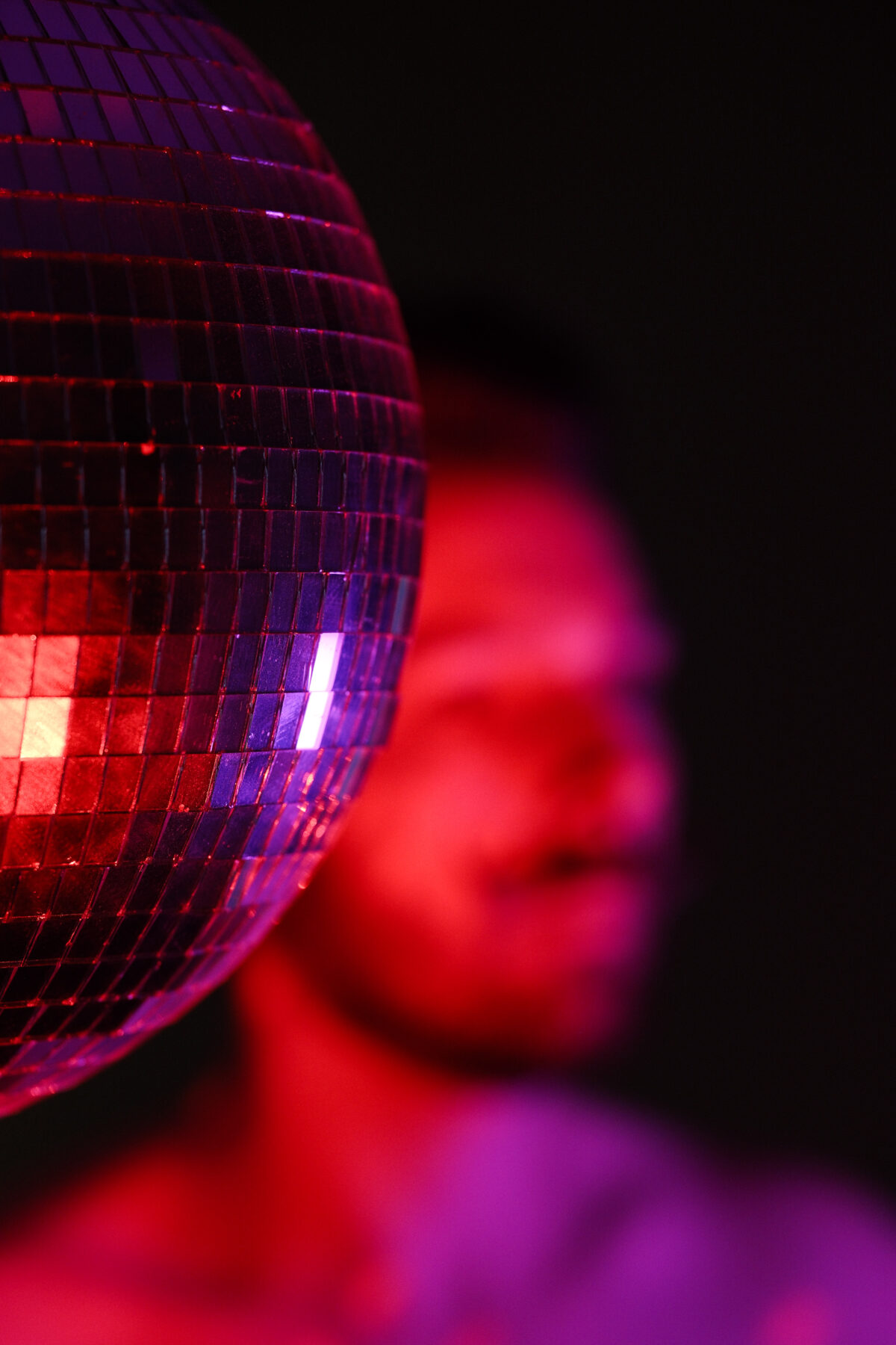 Boule à facettes en gros plan sous lumière rouge, silhouette de François floue en arrière-plan