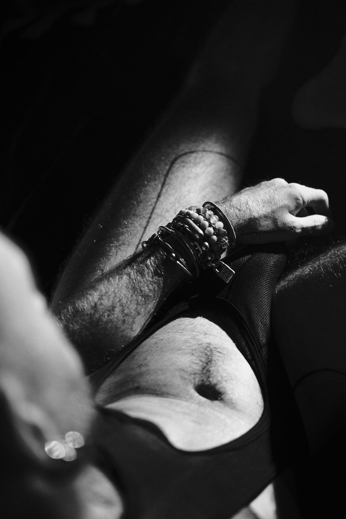 Gros plan en noir et blanc sur le bras et le torse de Hugo (de Lille), bracelets, débardeur en résille