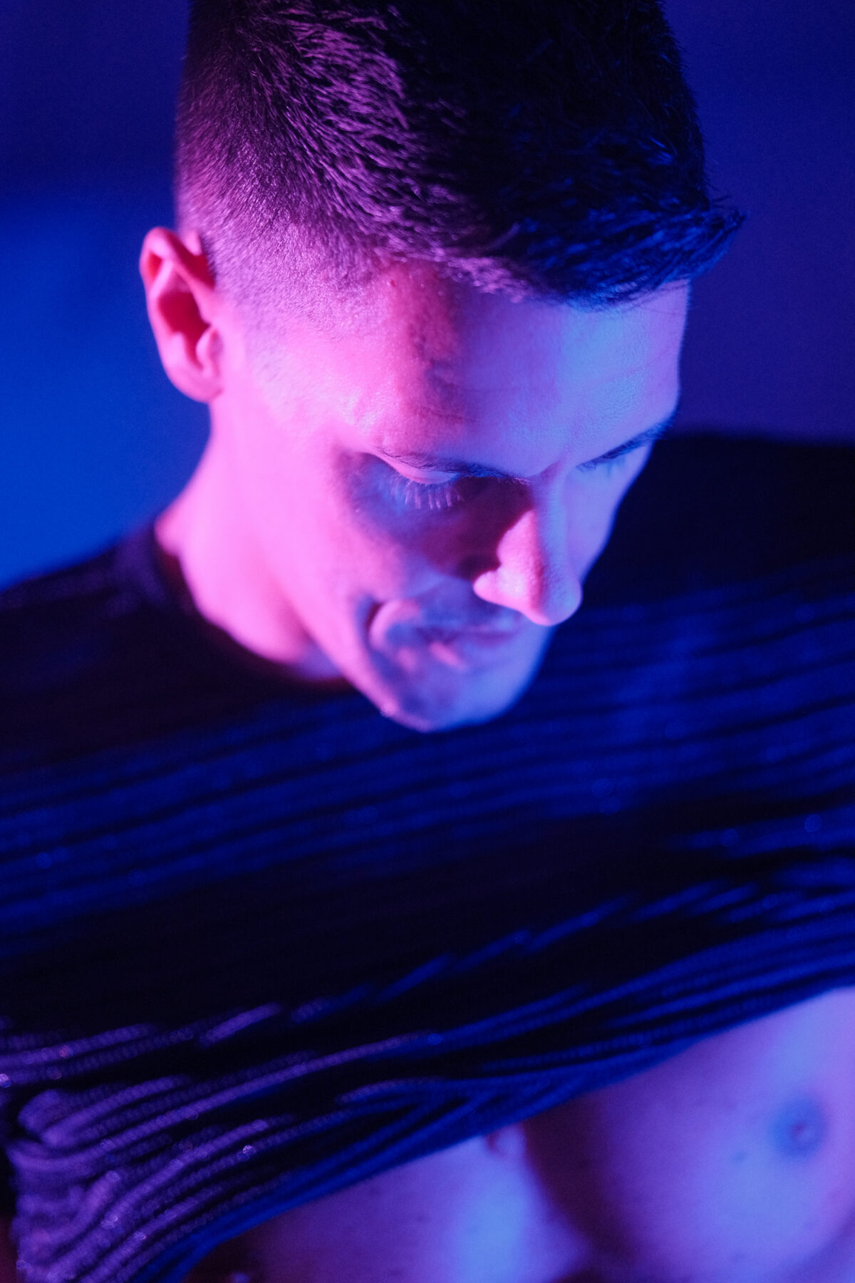 Gros plan abstrait sur la hanche d'un homme en sous-vêtement bleu clair, éclairage rose et bleu, photographie artistique sensuelle