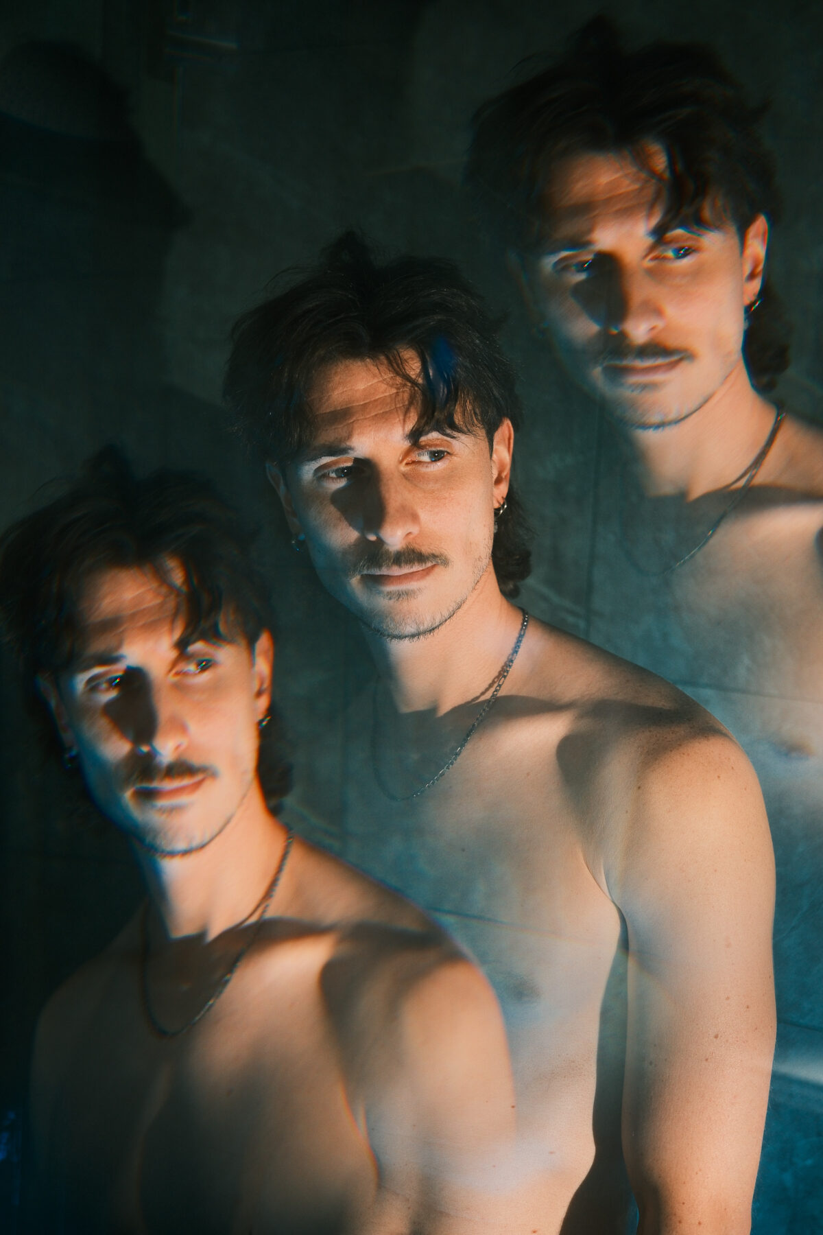 Portrait de Nico multiplié par un effet de reflets, trois visages superposés, collier fin, torse nu