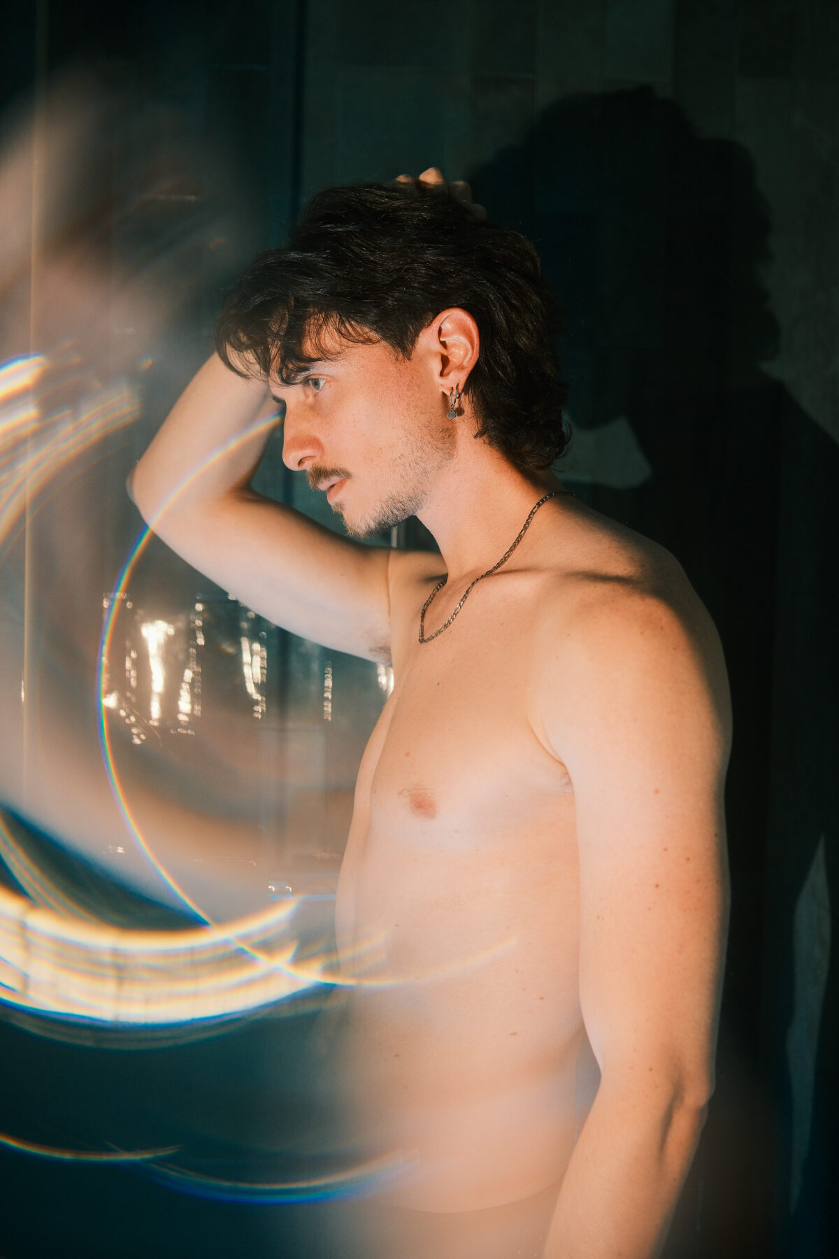 Portrait de Nico bras levé, effet de light painting coloré, collier visible, torse nu