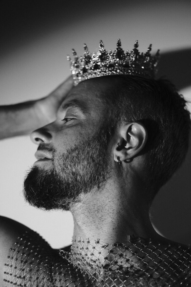 Portrait de profil de Pierre, couronne et piercings à l'oreille, harnais en résille strass, noir et blanc.